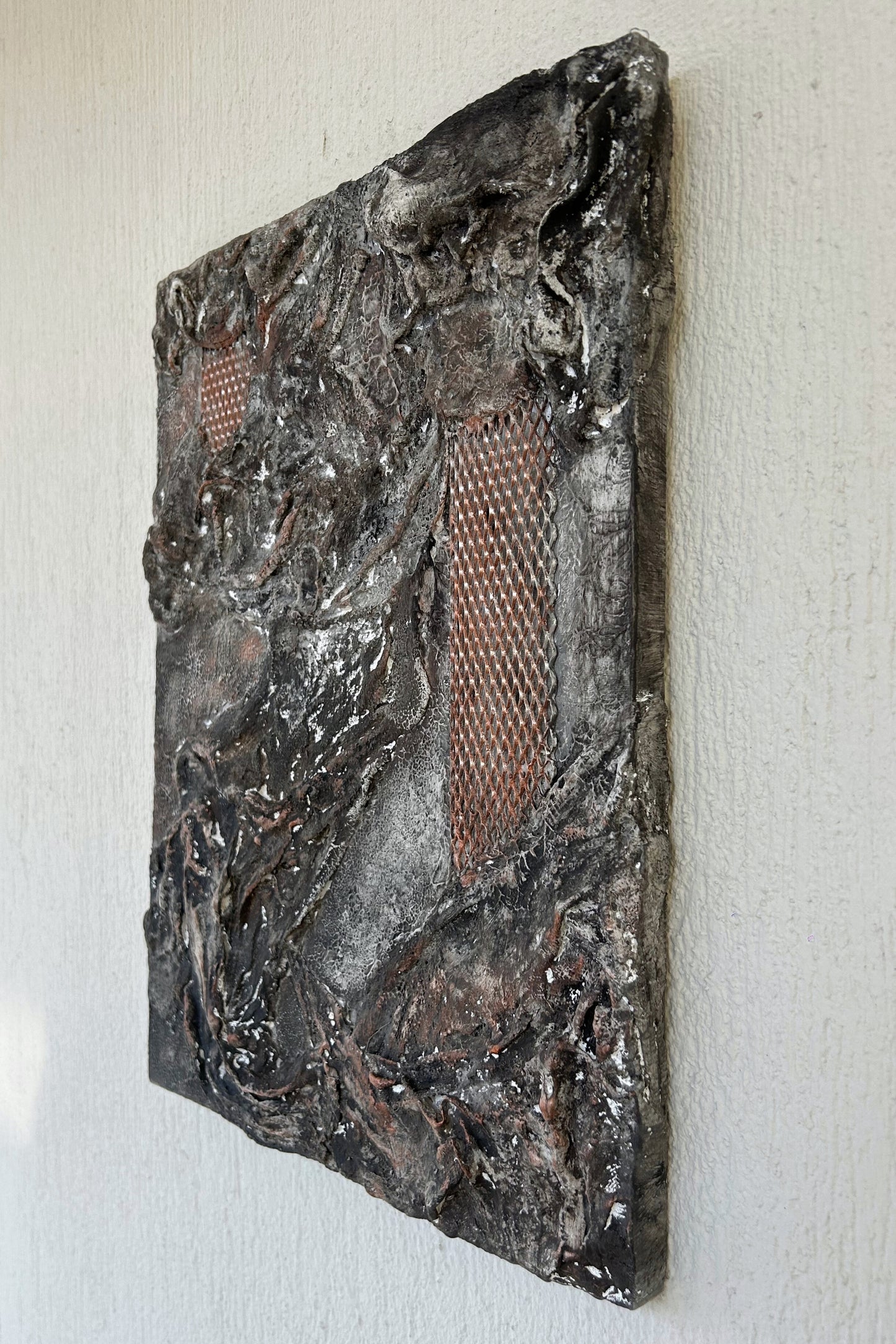 Angled close-up of handmade wall art showing intricate relief and cracked surface.