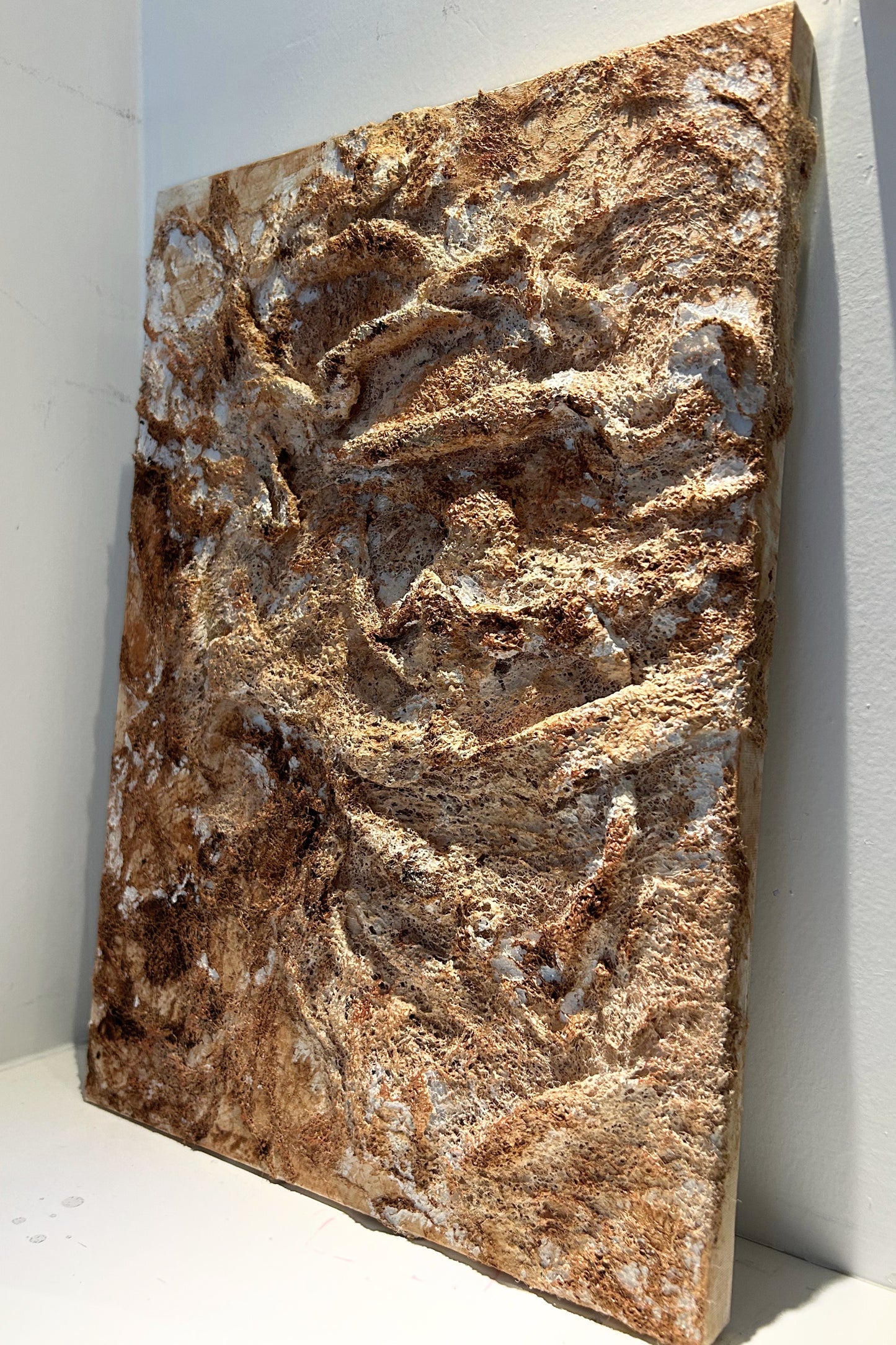 Angled view of handmade wall decor piece revealing copper highlights and texture.