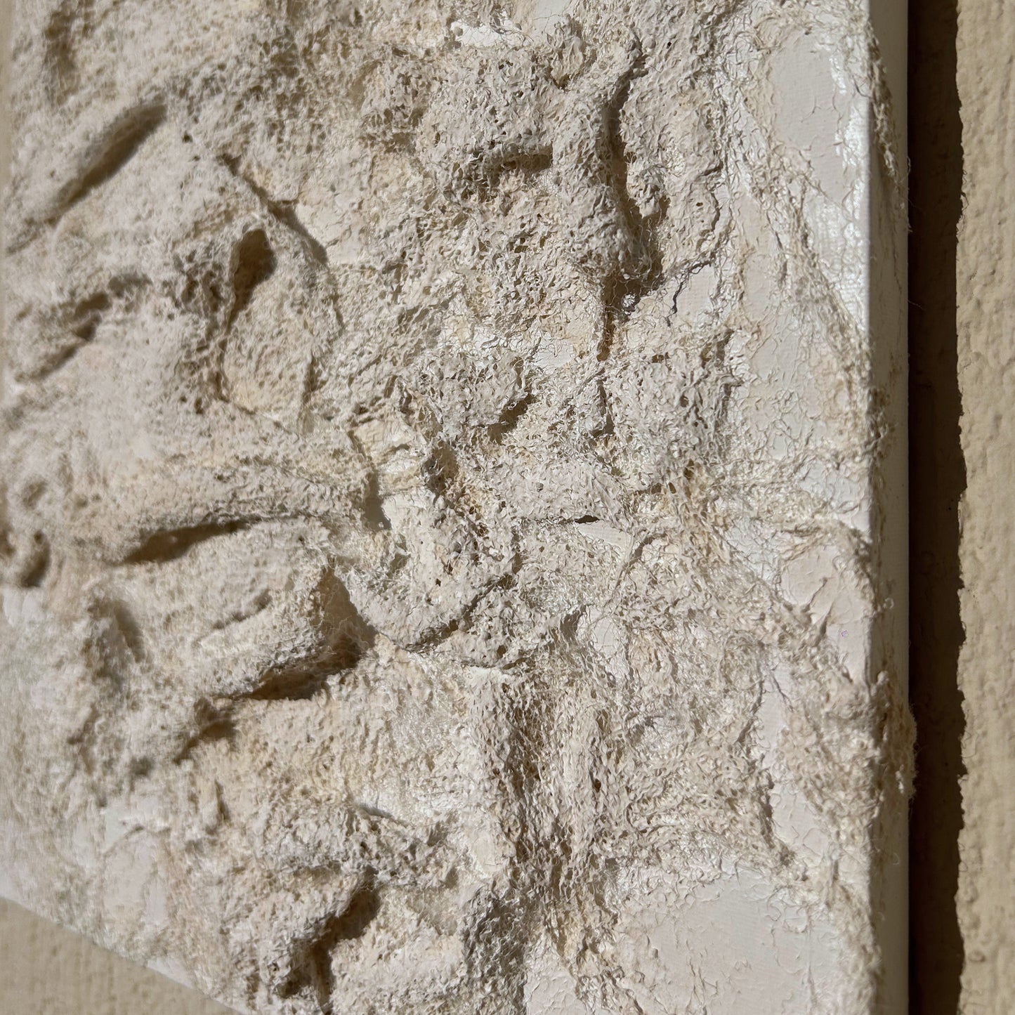 Side angle showing the depth and movement in the handmade white textured canvas wall piece.