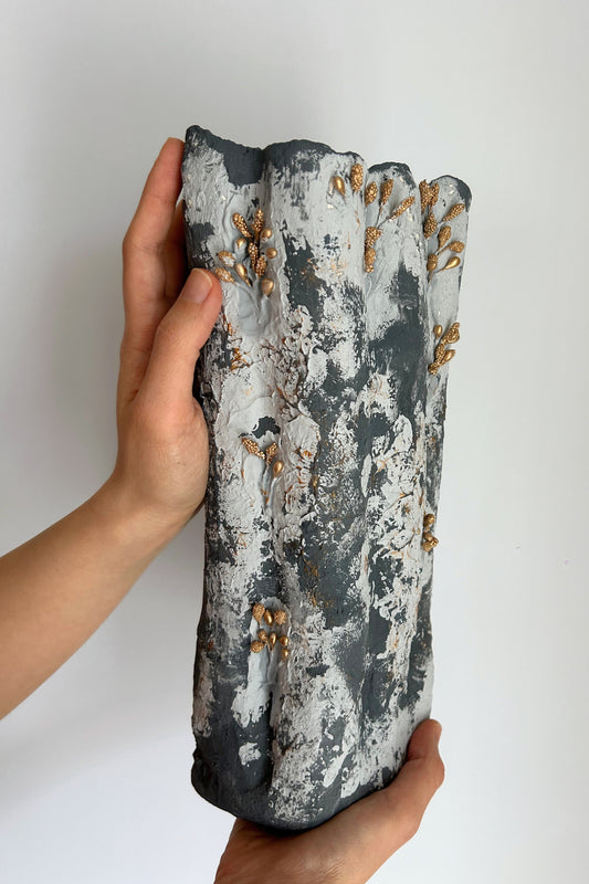 Eco-friendly tall vase with white and dark plaster layers, held upright with gold sculpted beads.
