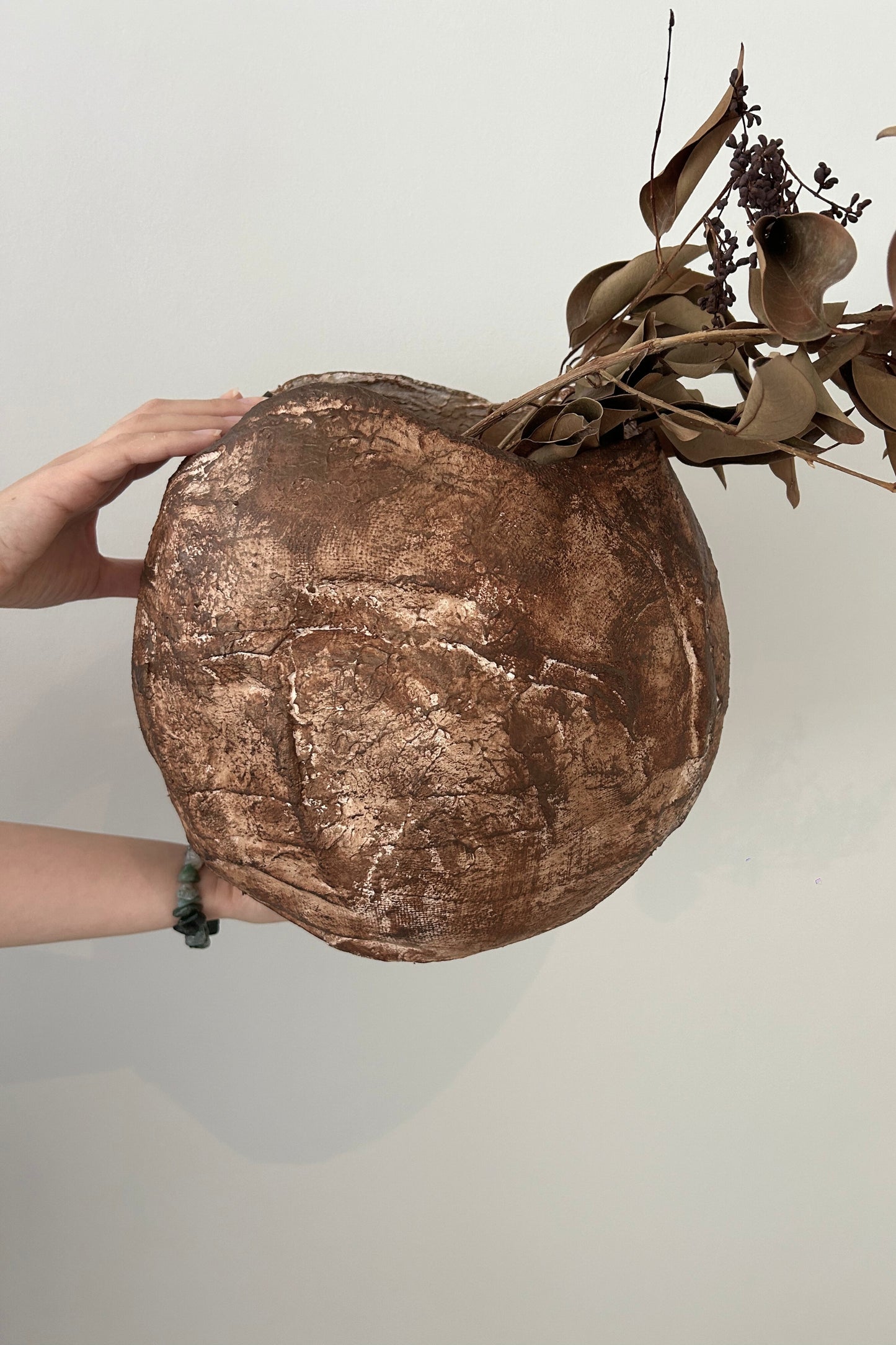 Handmade rustic vase held in hand to show its scale and texture-rich finish.
