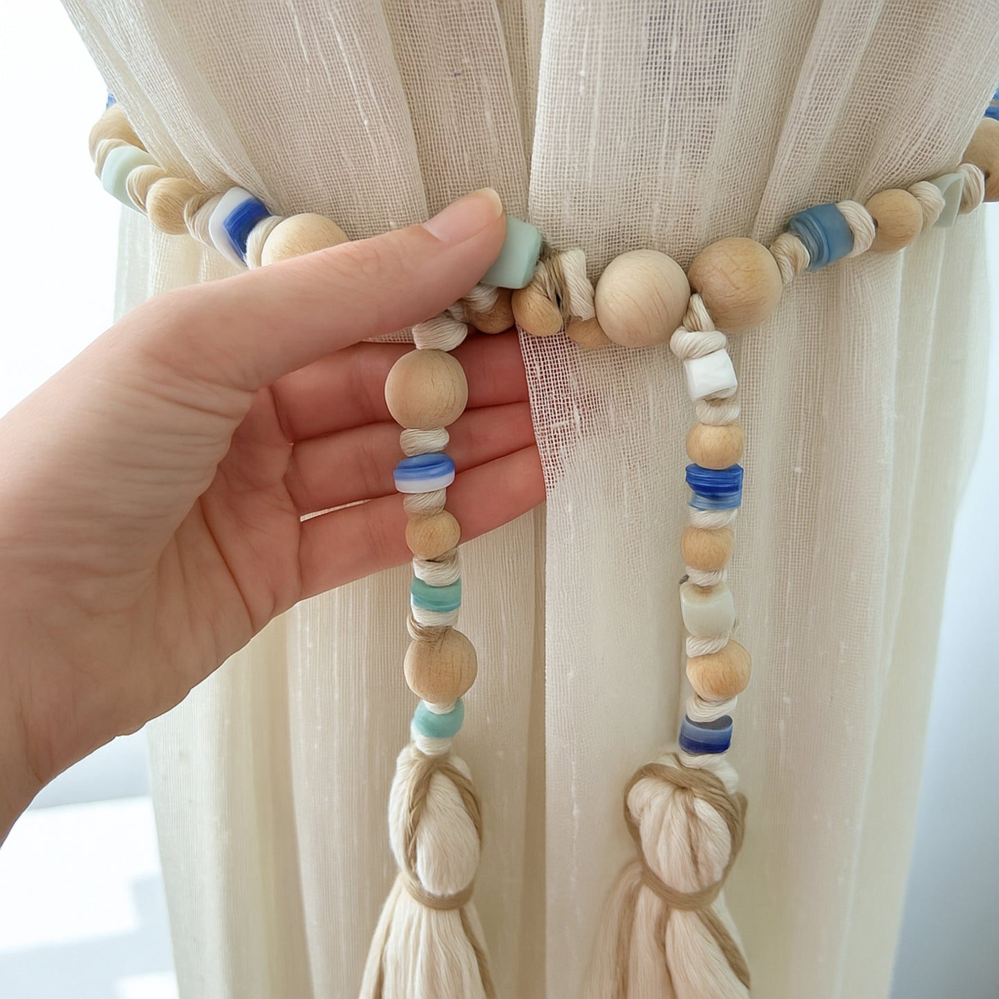 Close-up of curtain styling using handmade bead garland with boho macrame tassels.