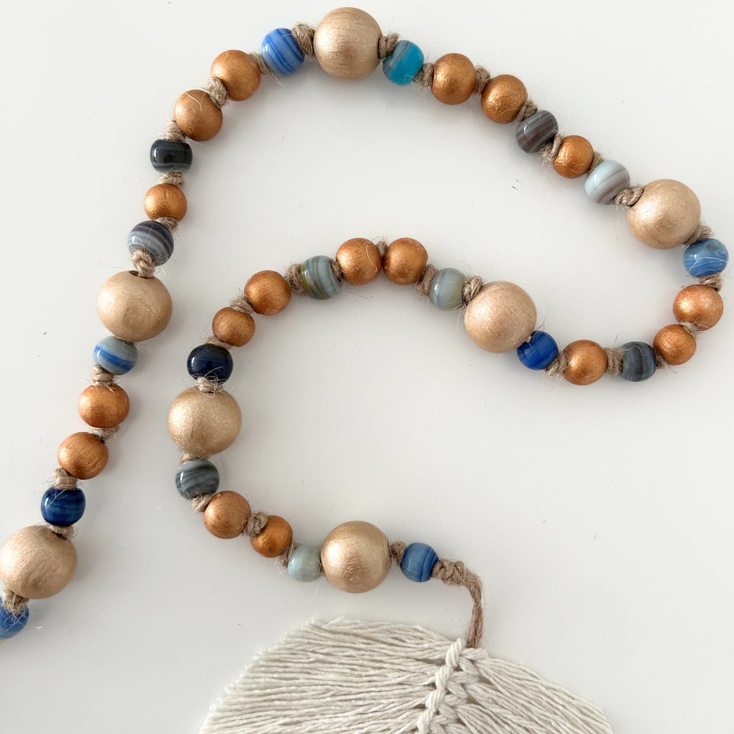 Beaded garland with natural wood and blue glass beads on a clean white surface