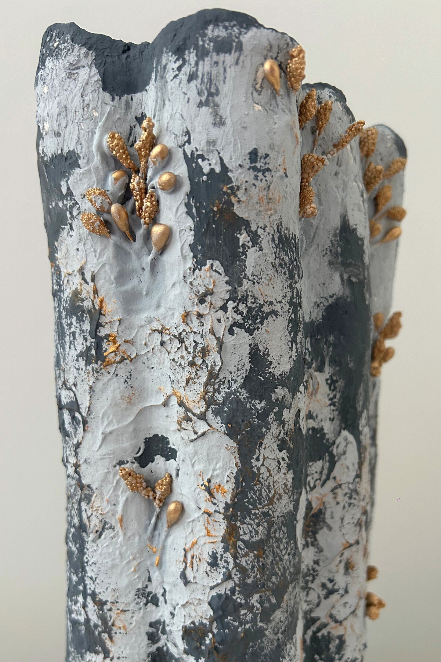 Close-up of top rim and golden accents on handmade textured wabi sabi vase.