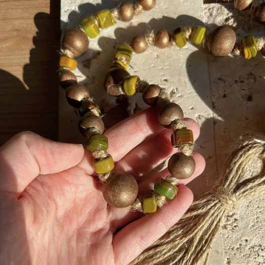 Close-up of artisan glass and wood beads showing texture and earthy tones.