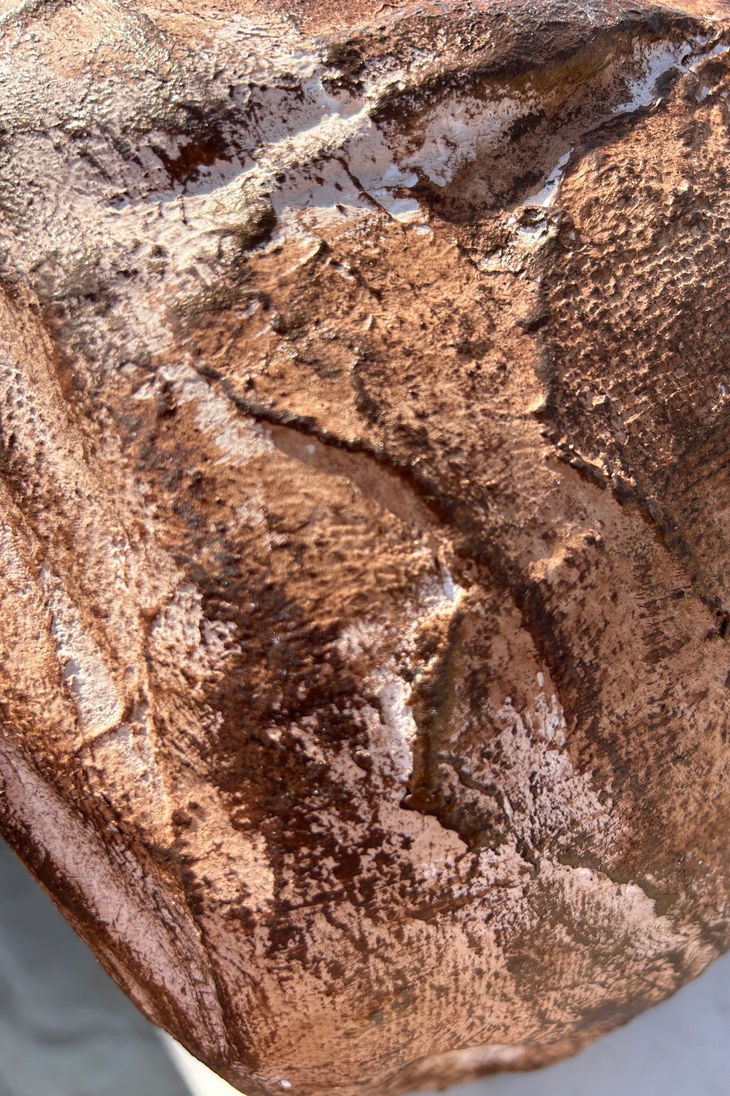 Close-up of aged bronze surface texture and layered sculptural pattern on the vase body.