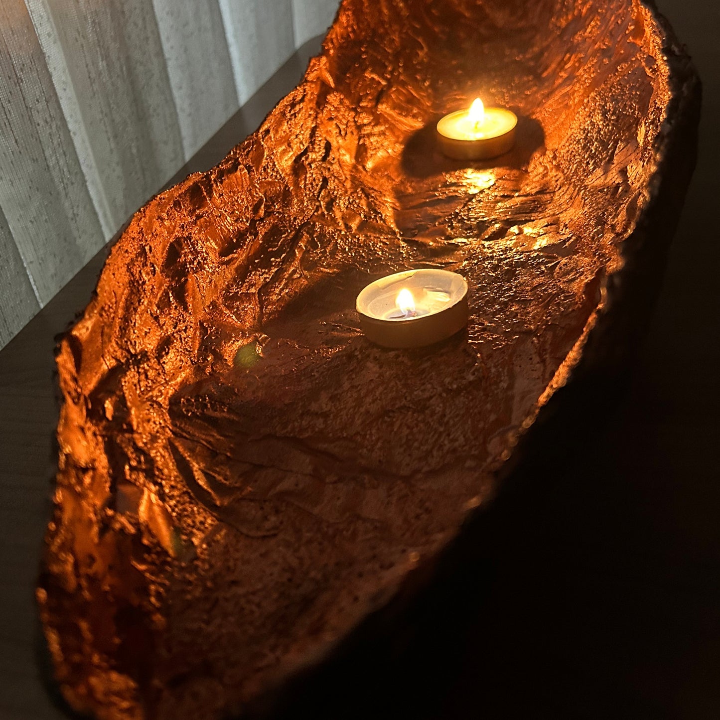 Glowing copper interior of handmade bowl illuminated with warm candlelight tones.