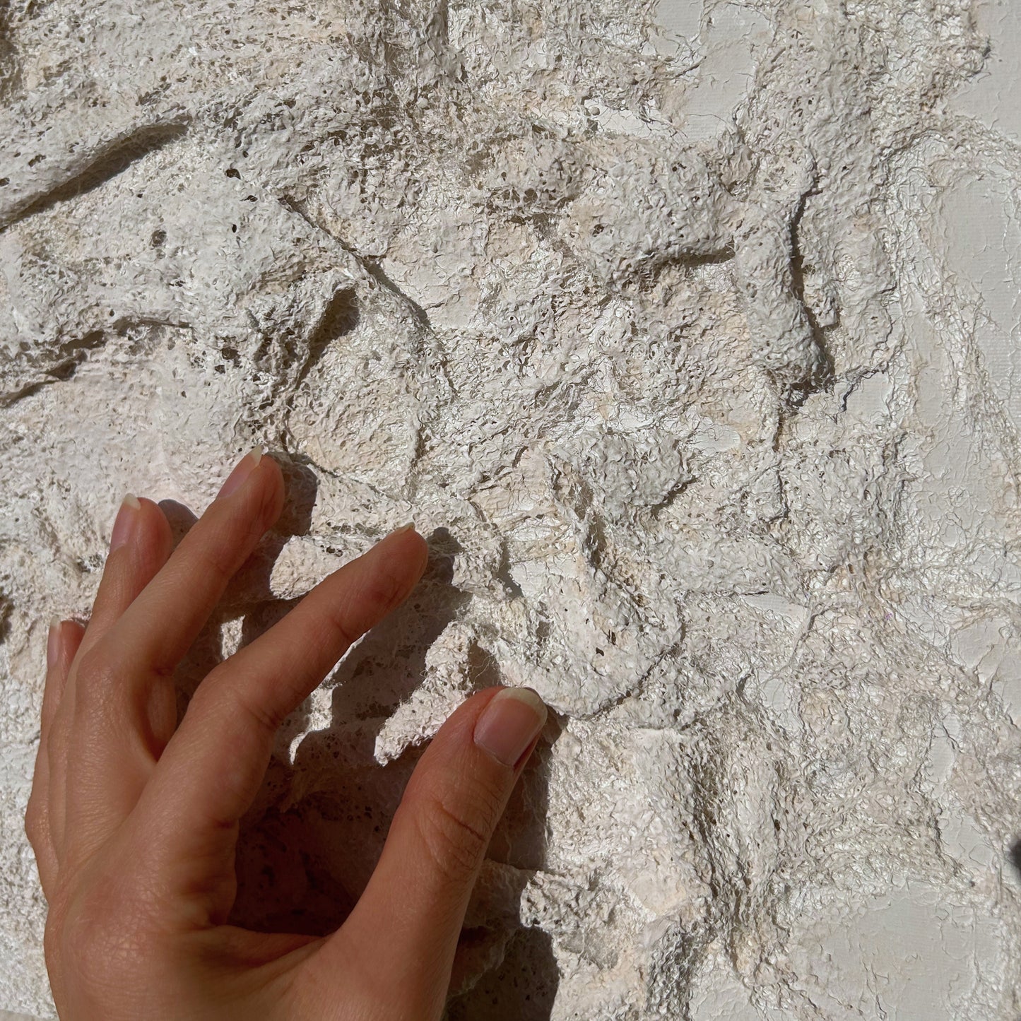 Close-up of the layered fabric and plaster texture, capturing the organic 3D relief of the artwork.