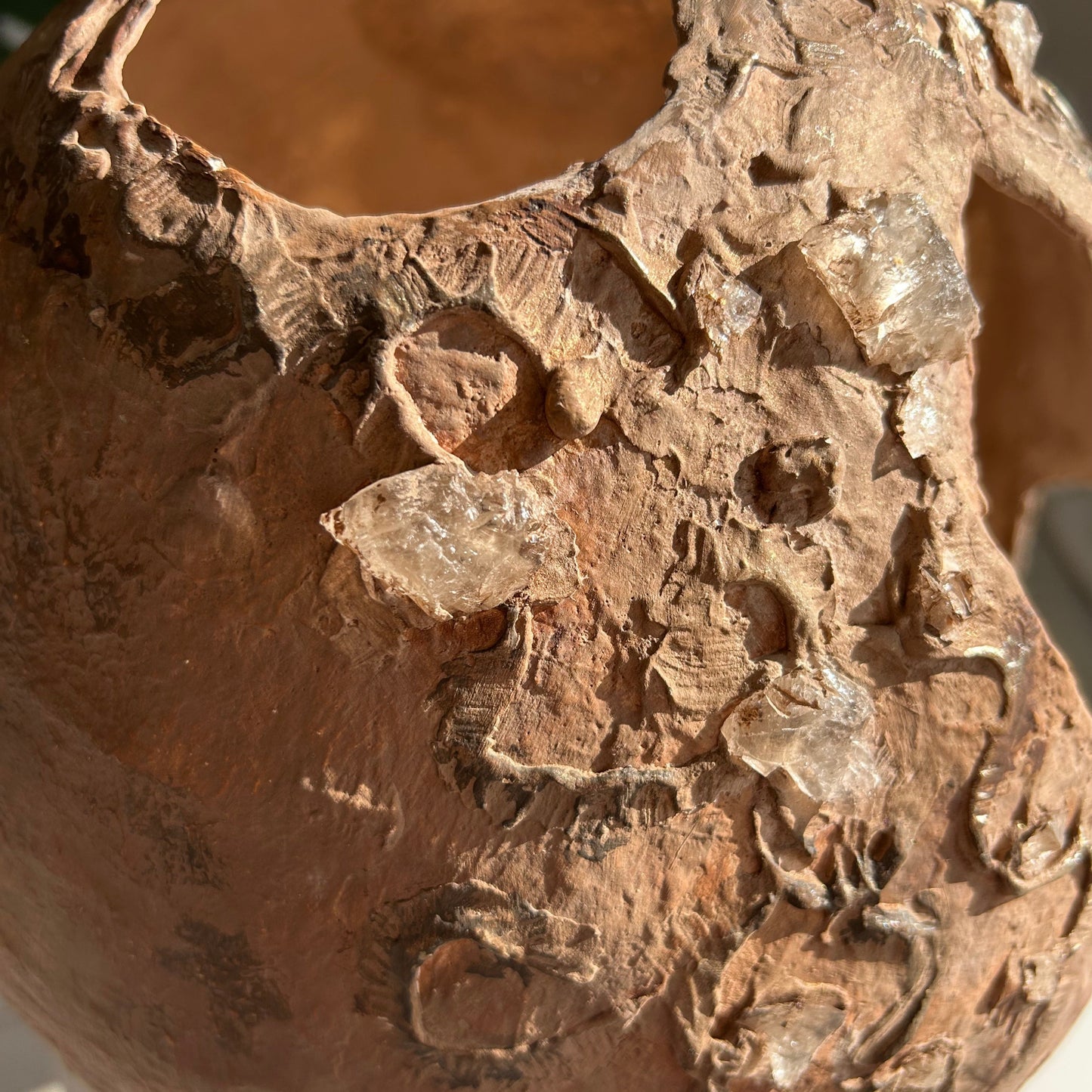 Smoky quartz and sculpted relief details on clay surface of wabi sabi decorative vase – close-up