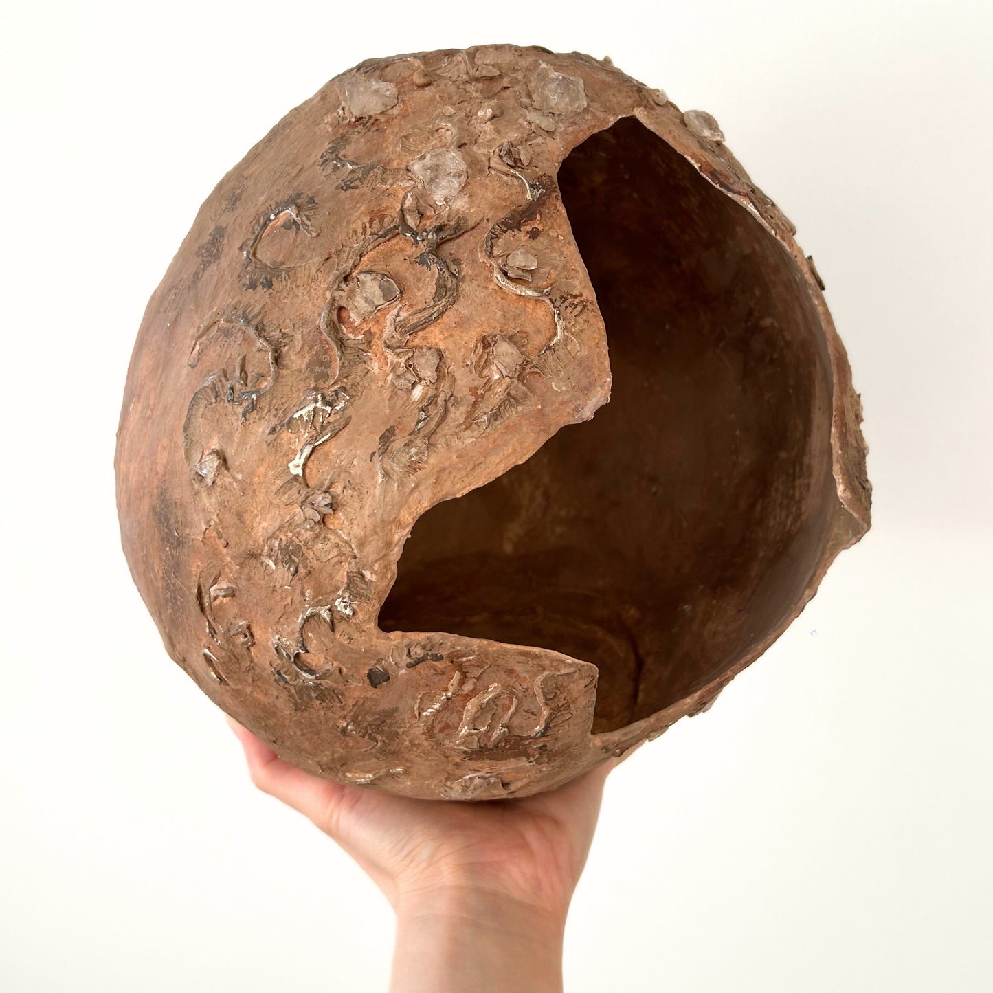 Handmade rounded vase with sculptural detailing held in hand – showing broken-edge design