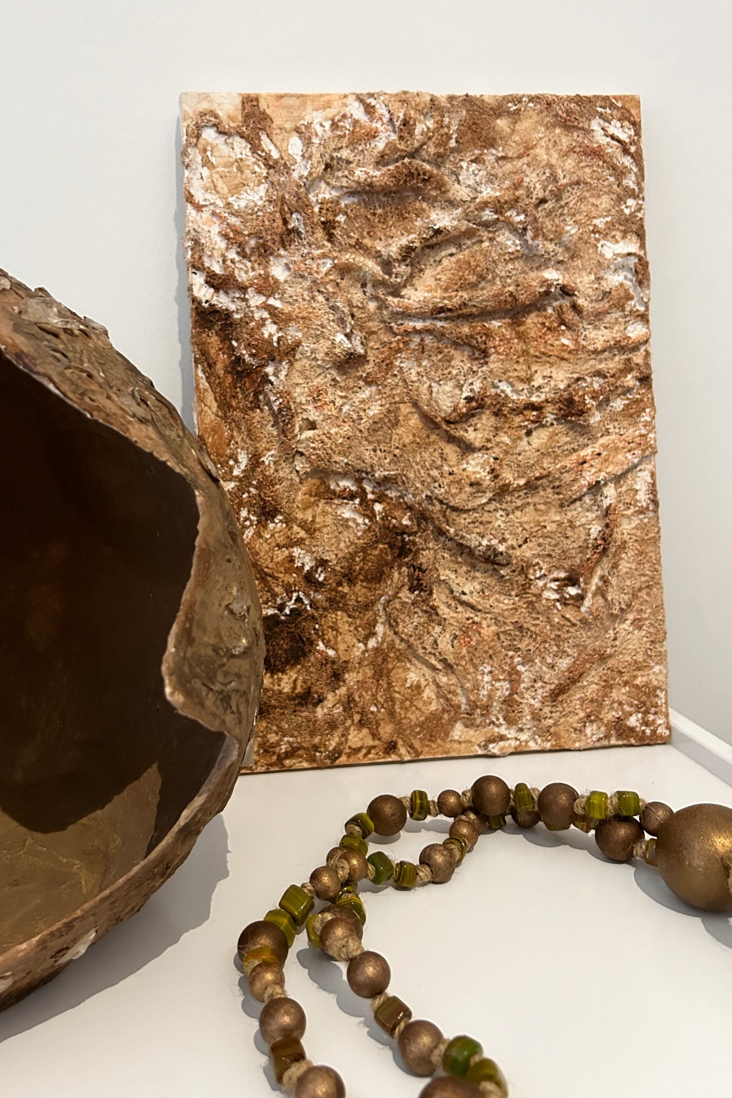 Styled scene with wall art, wood beads, and ceramics reflecting natural harmony.