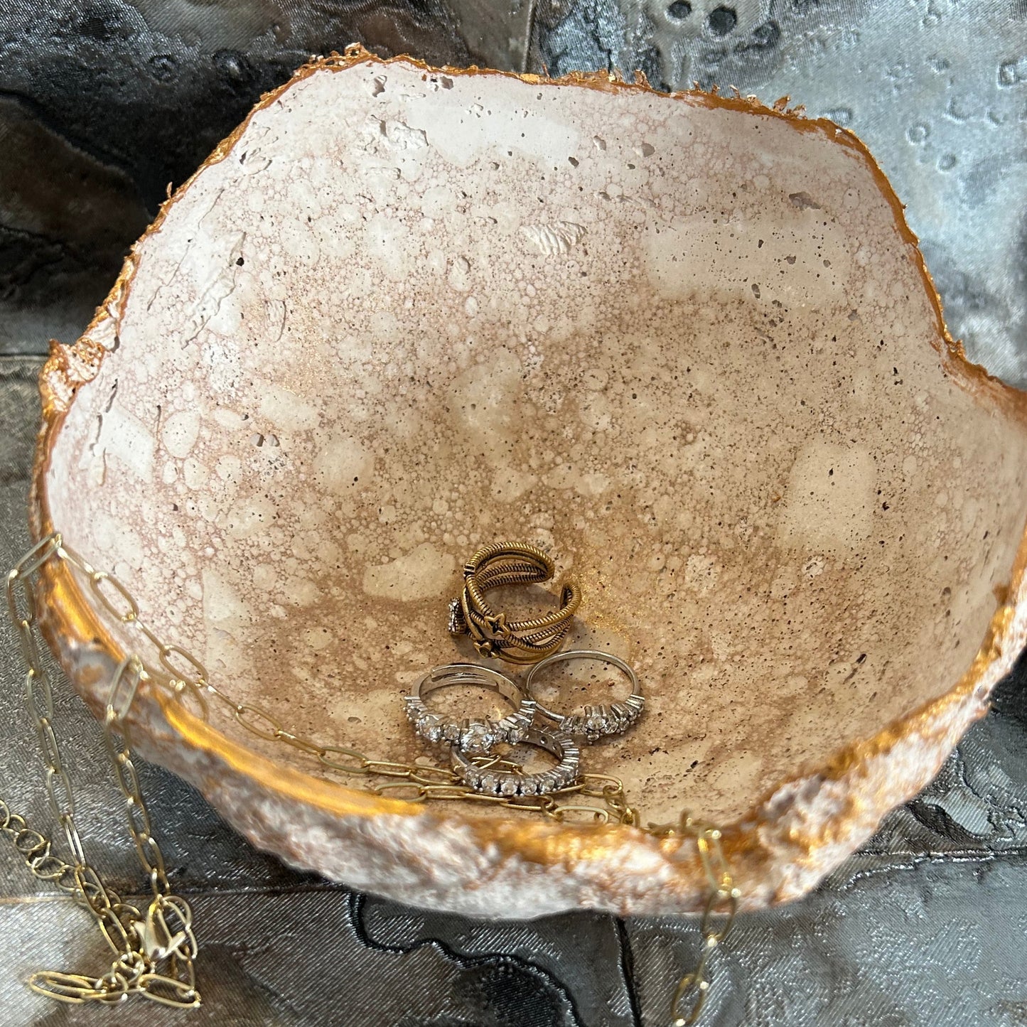 Interior view of the decorative bowl filled with rings and styled on marbled background.