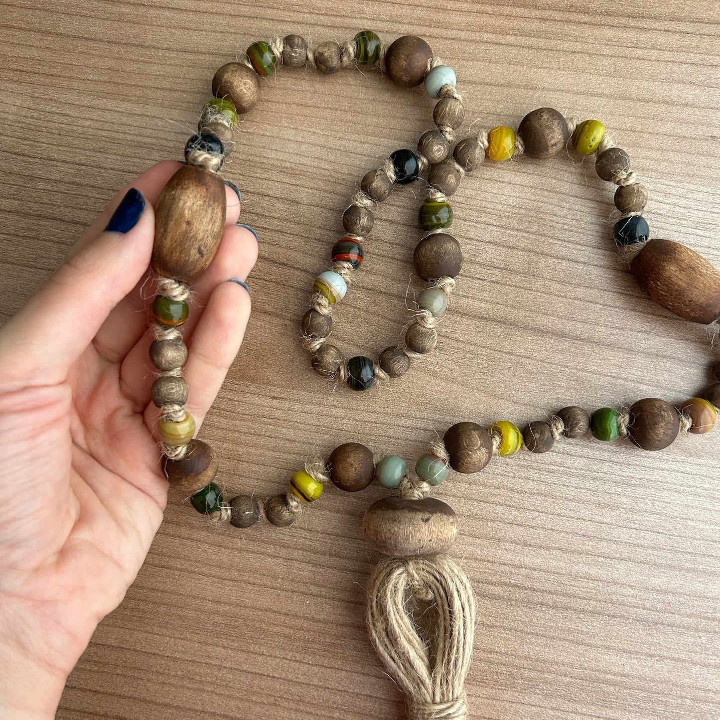 Hand holding rustic boho bead garland with jute tassel