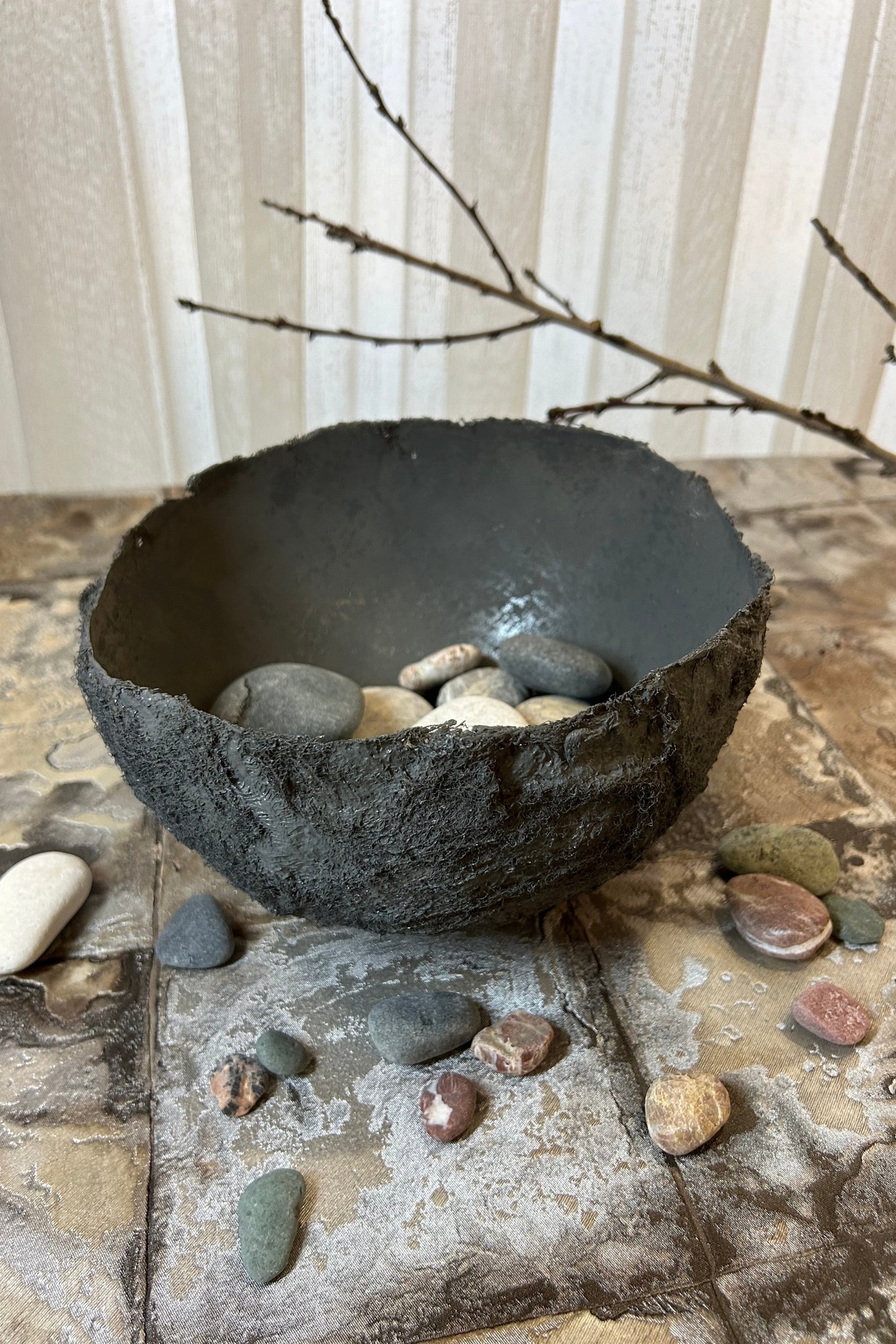 Eco-friendly wabi sabi bowl styled with natural pebbles and dried branches.