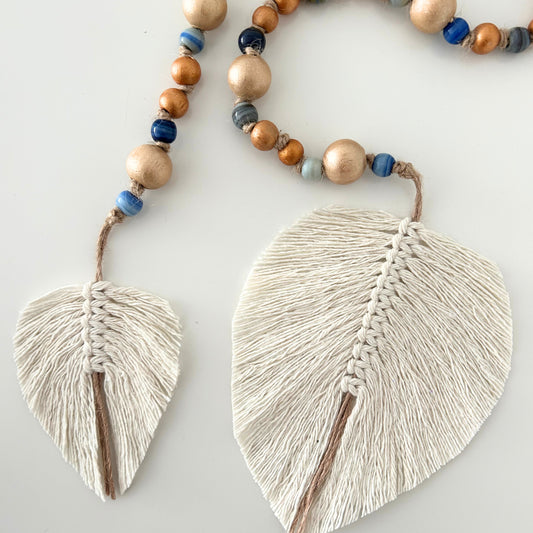 Close view of dual jute leaf tassels with handcrafted beads against a white background