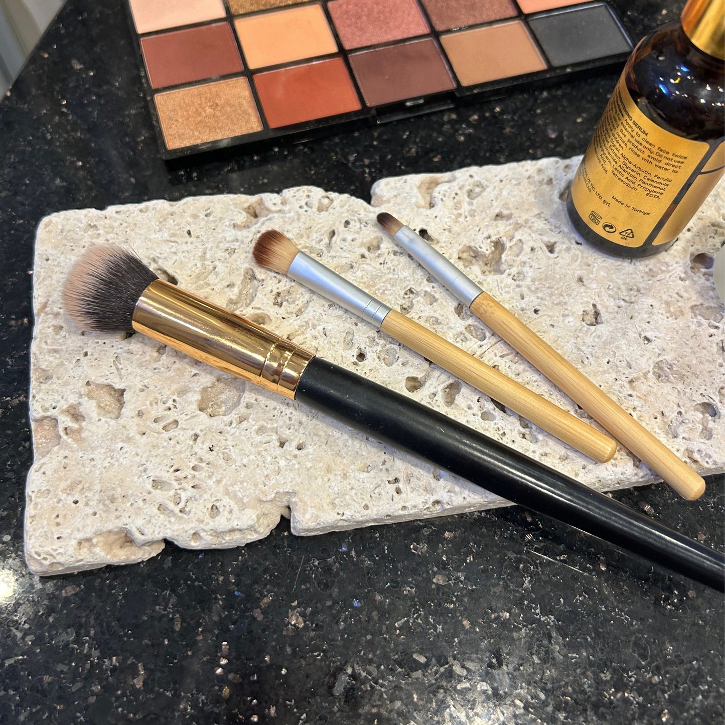 Skincare and beauty props arranged with travertine styling slabs and brushes
