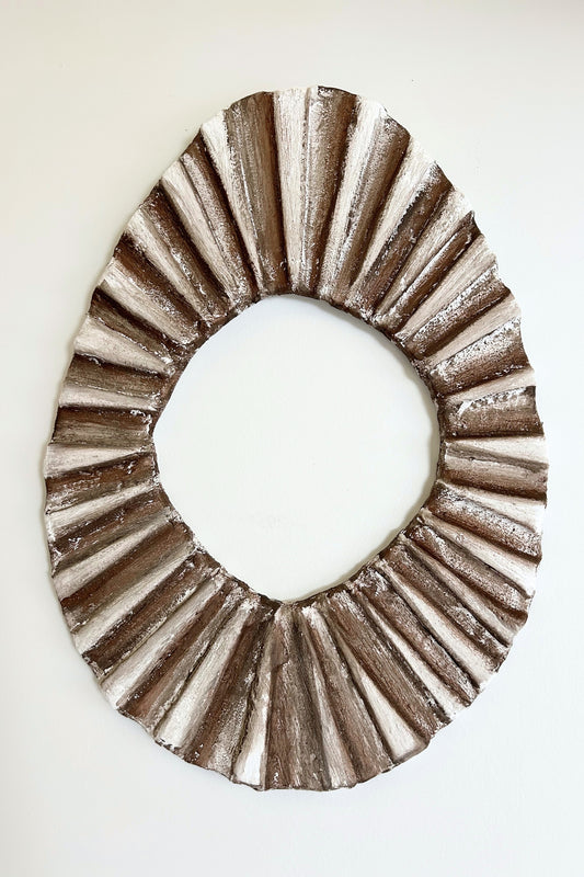 Full frontal view of sculptural oval wall frame in minimalist clay finish