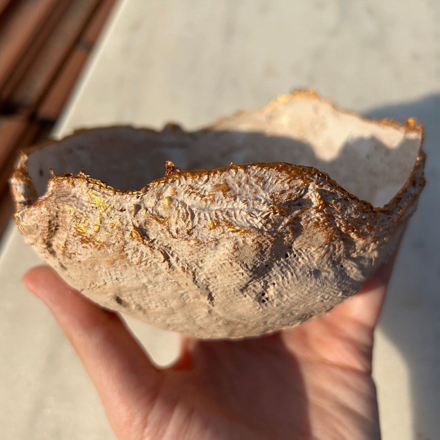 Organic rim and layered surface of the rustic bowl captured under direct light.