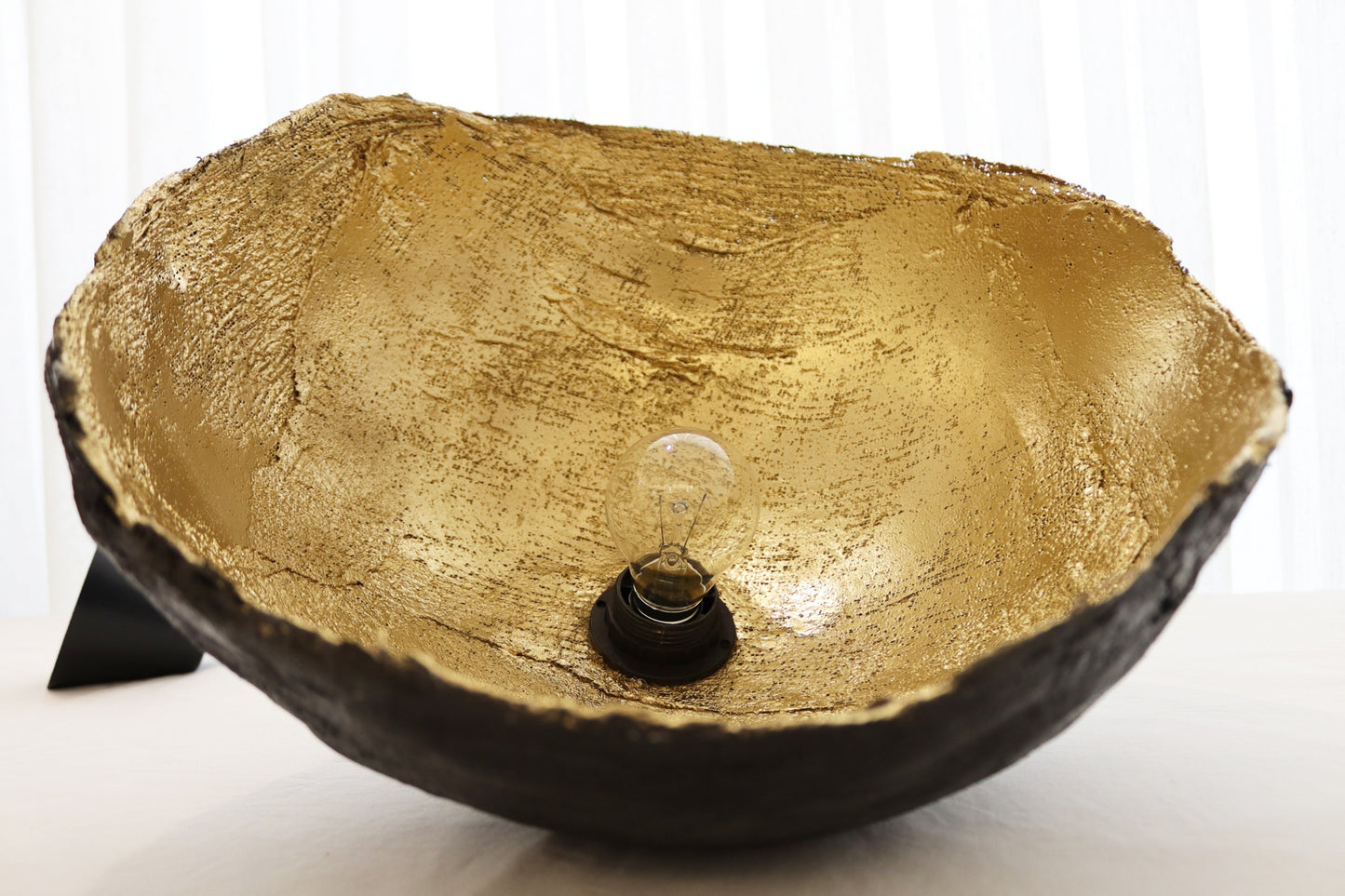 Golden inside surface of wabi-sabi ceiling lamp showing rich texture and light reflection