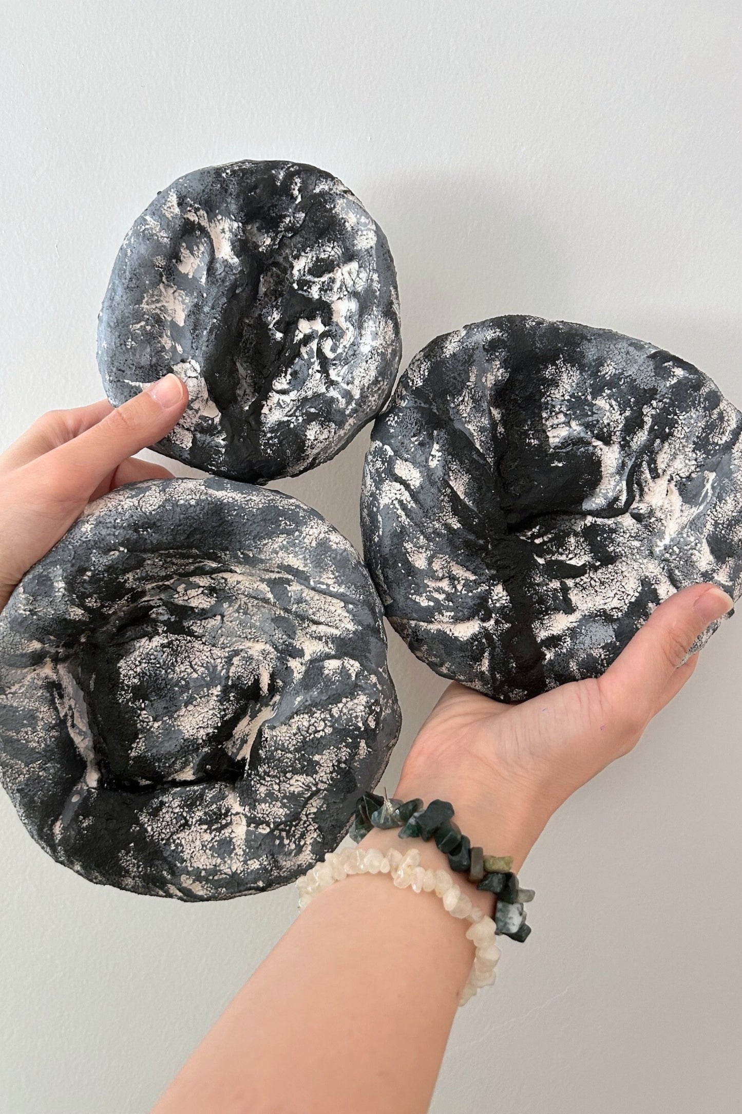 Hand holding all three textured round plaster wall sculptures