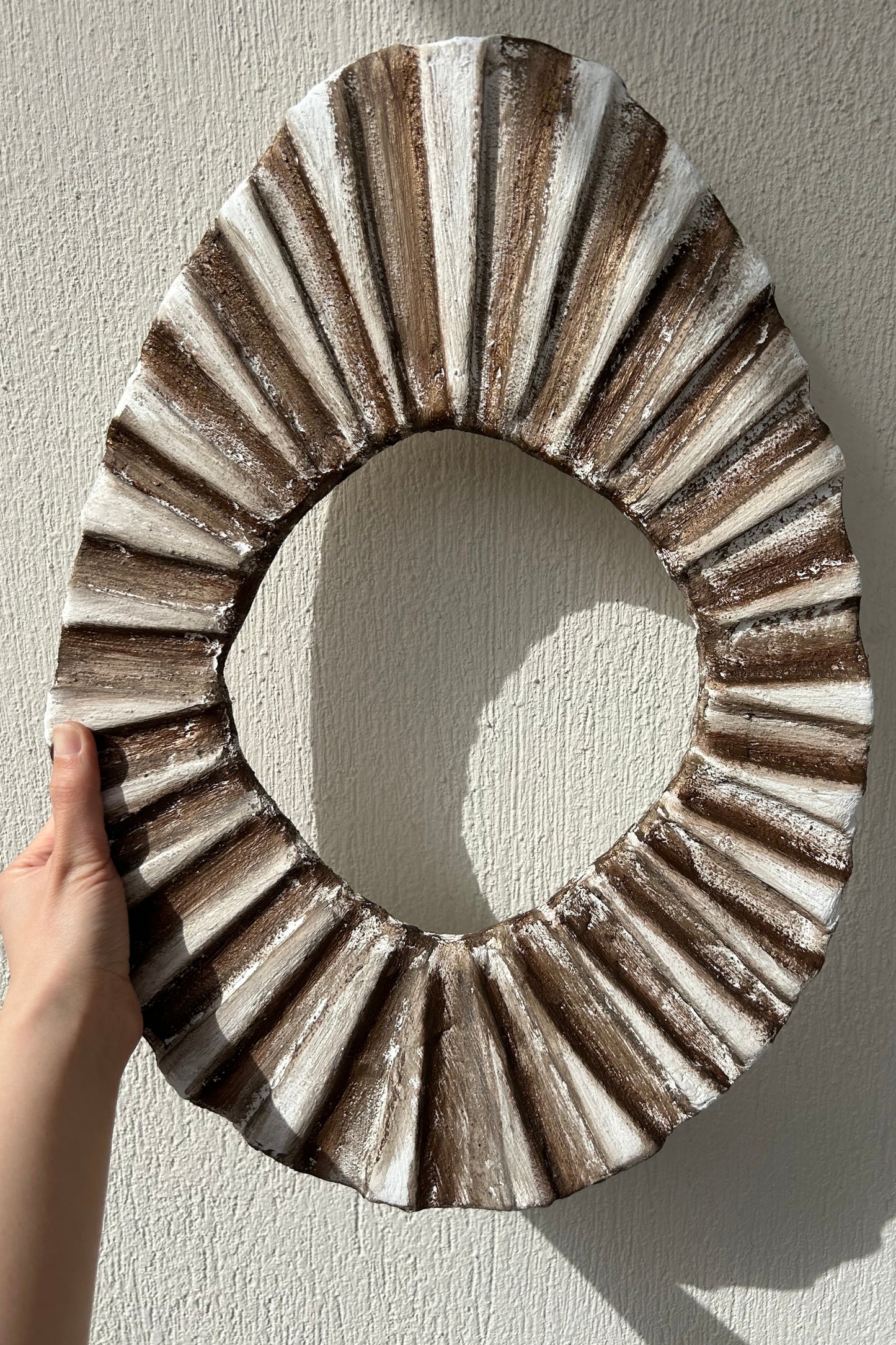Wall sculpture held in hand for size reference and texture visibility
