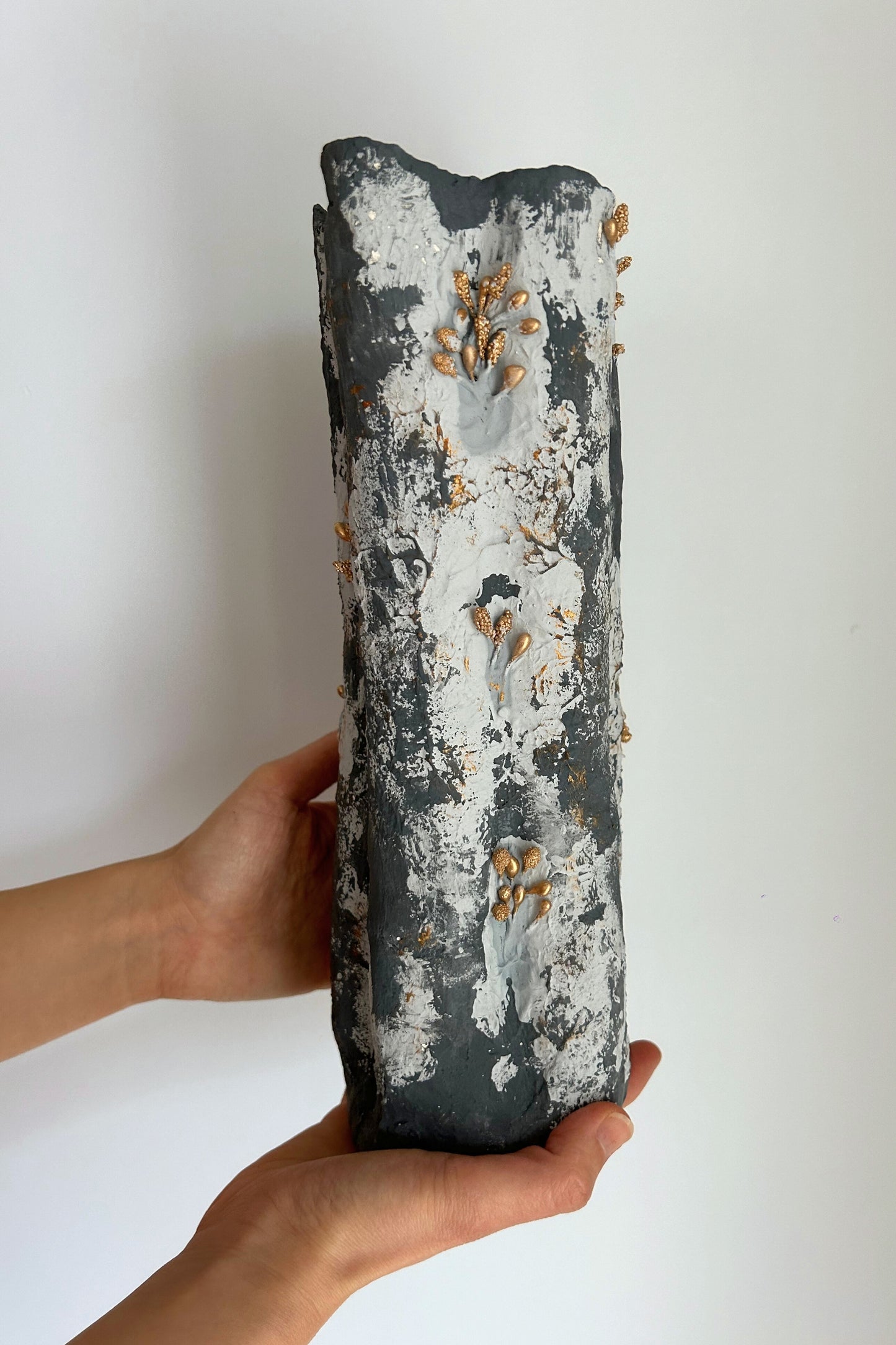 Handmade blue vase held by two hands, showing the natural textured finish and artistic form.