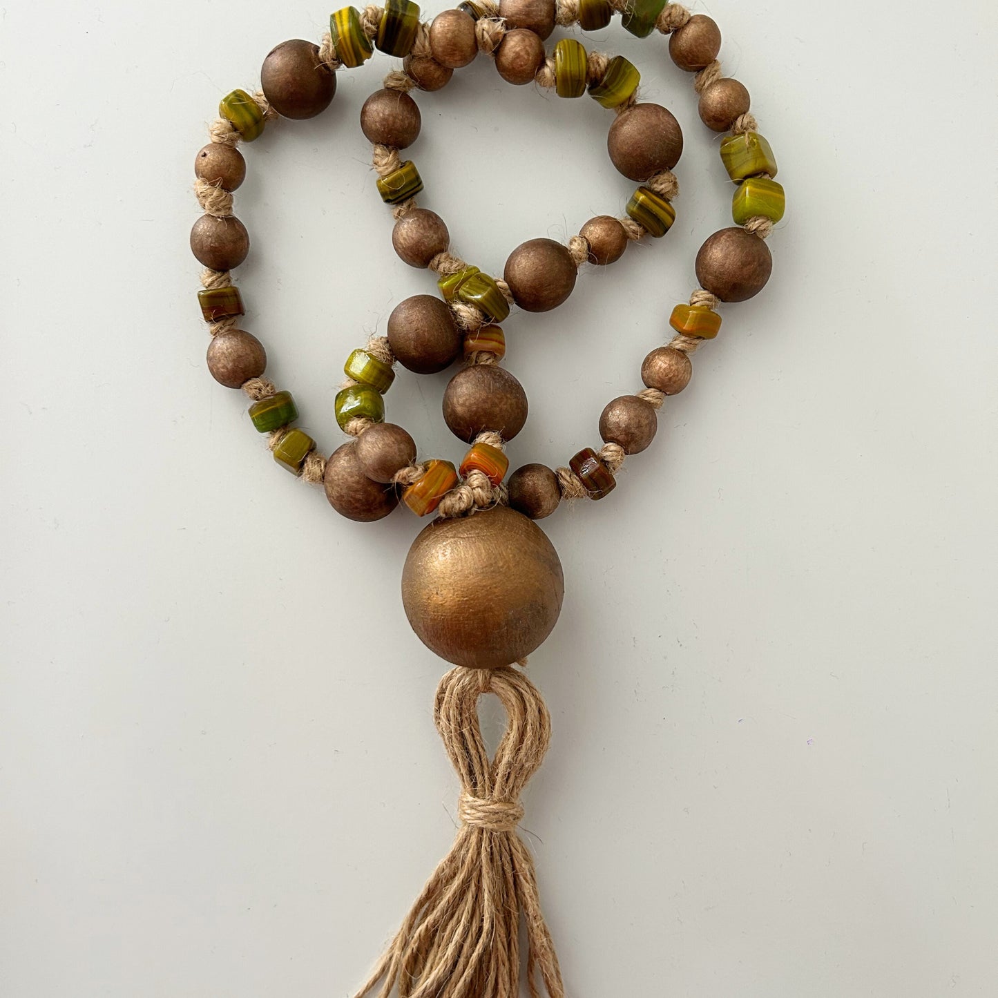 Earth-toned wood and glass bead garland displayed on a tabletop surface.