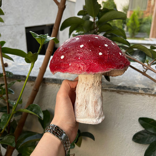 Hand-holding view of the mushroom sculpture in outdoor garden setting