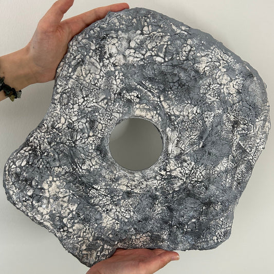 Organic modern wall sculpture displayed against light wall background