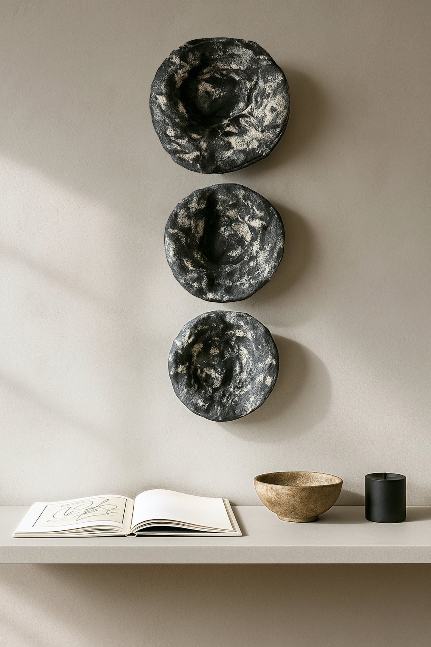 Two handmade round plaster wall pieces styled vertically above a console table