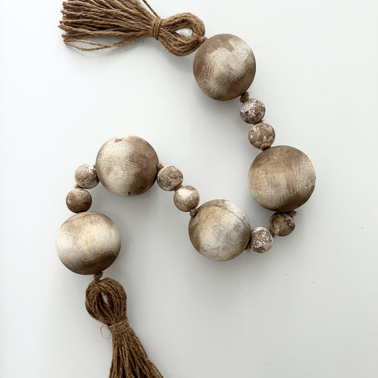 Handmade wooden bead garland with jute tassel styled on white background