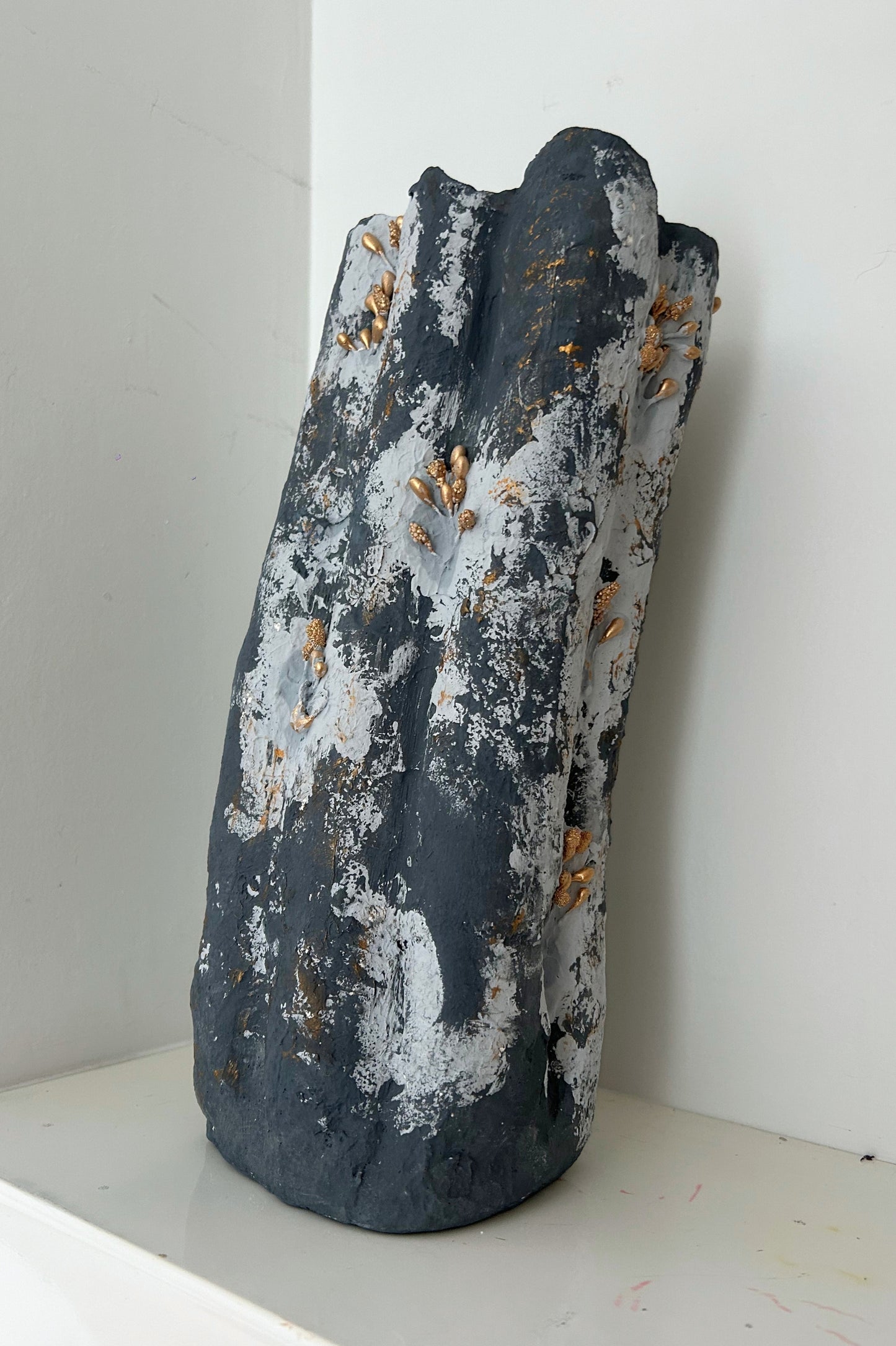 Handmade tall blue textured vase with sculptural gold details, front view on a neutral background.
