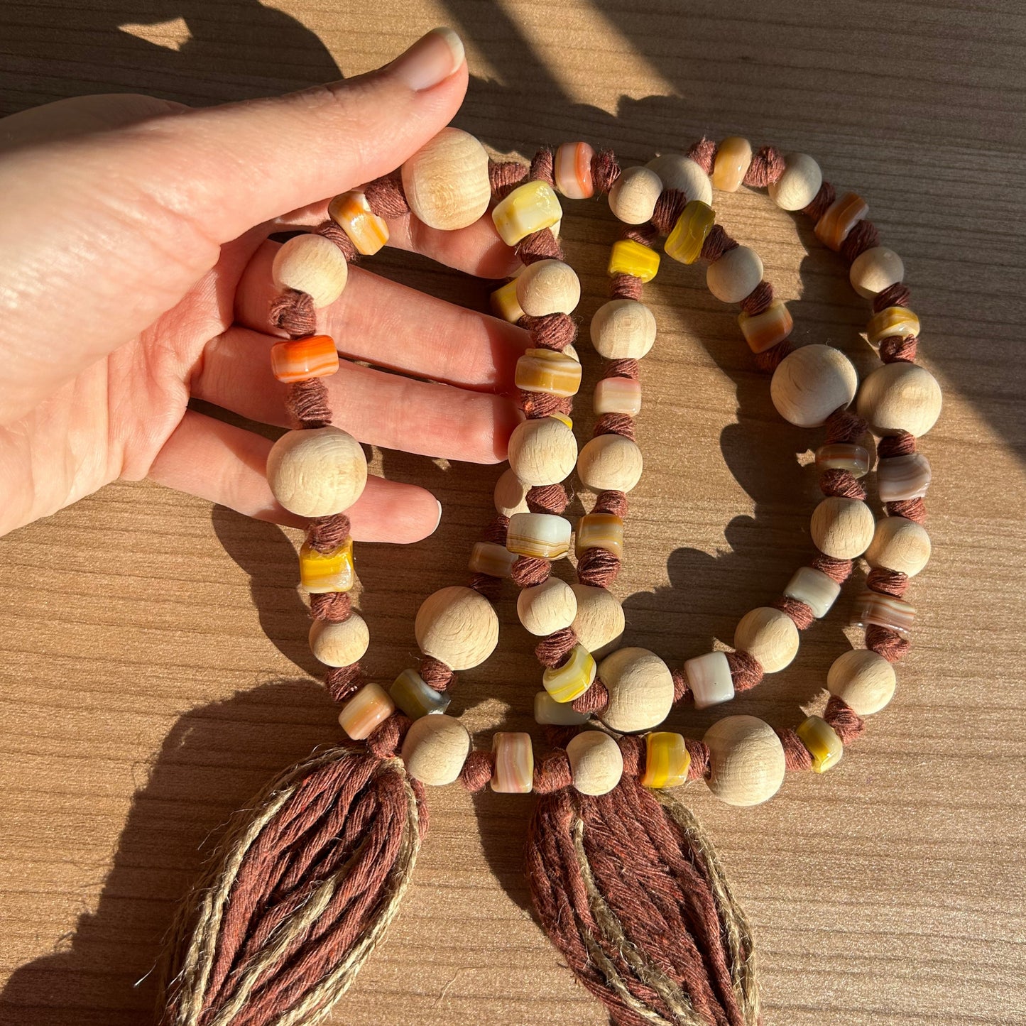 Hand holding natural curtain garland with rustic jute and boho beads