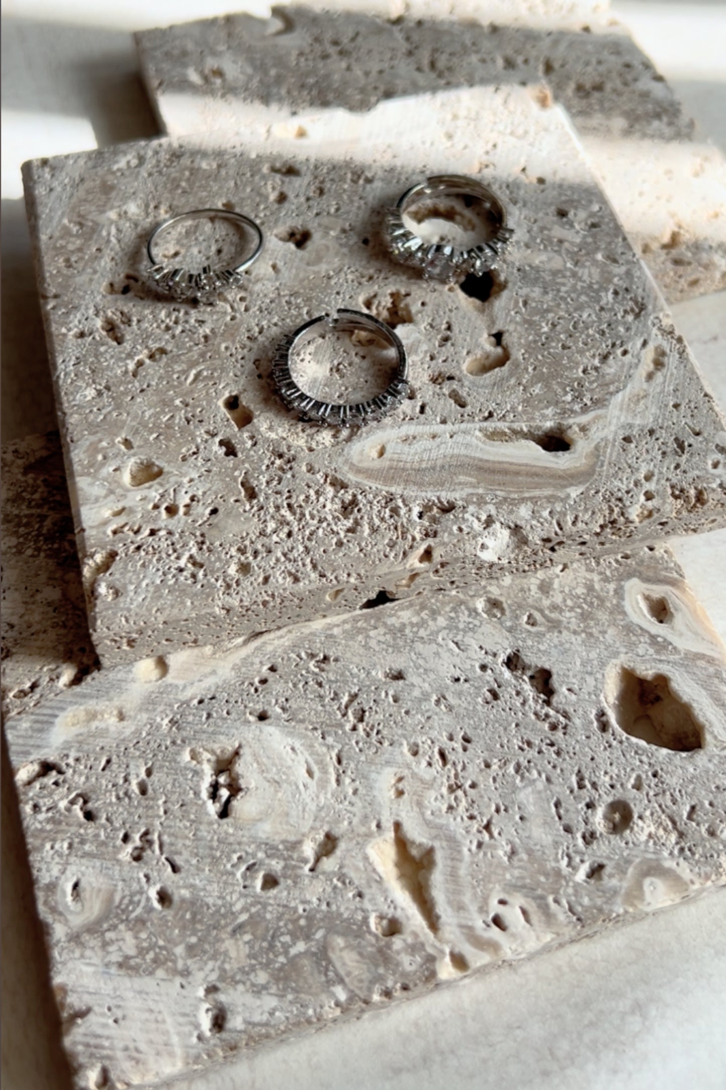 Necklaces and rings styled on natural travertine photo props