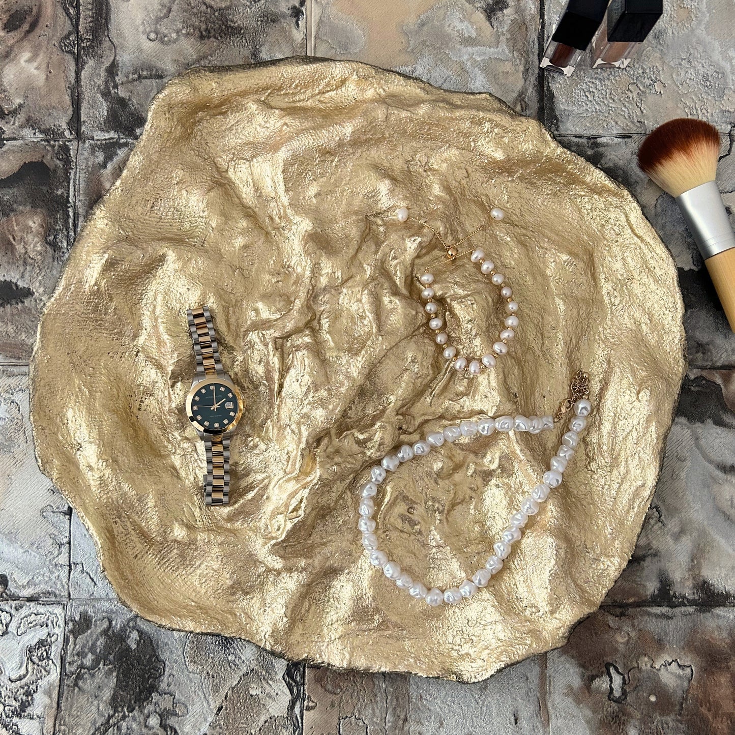 Gold accent bowl holding jewelry pieces, showcasing its functional design
