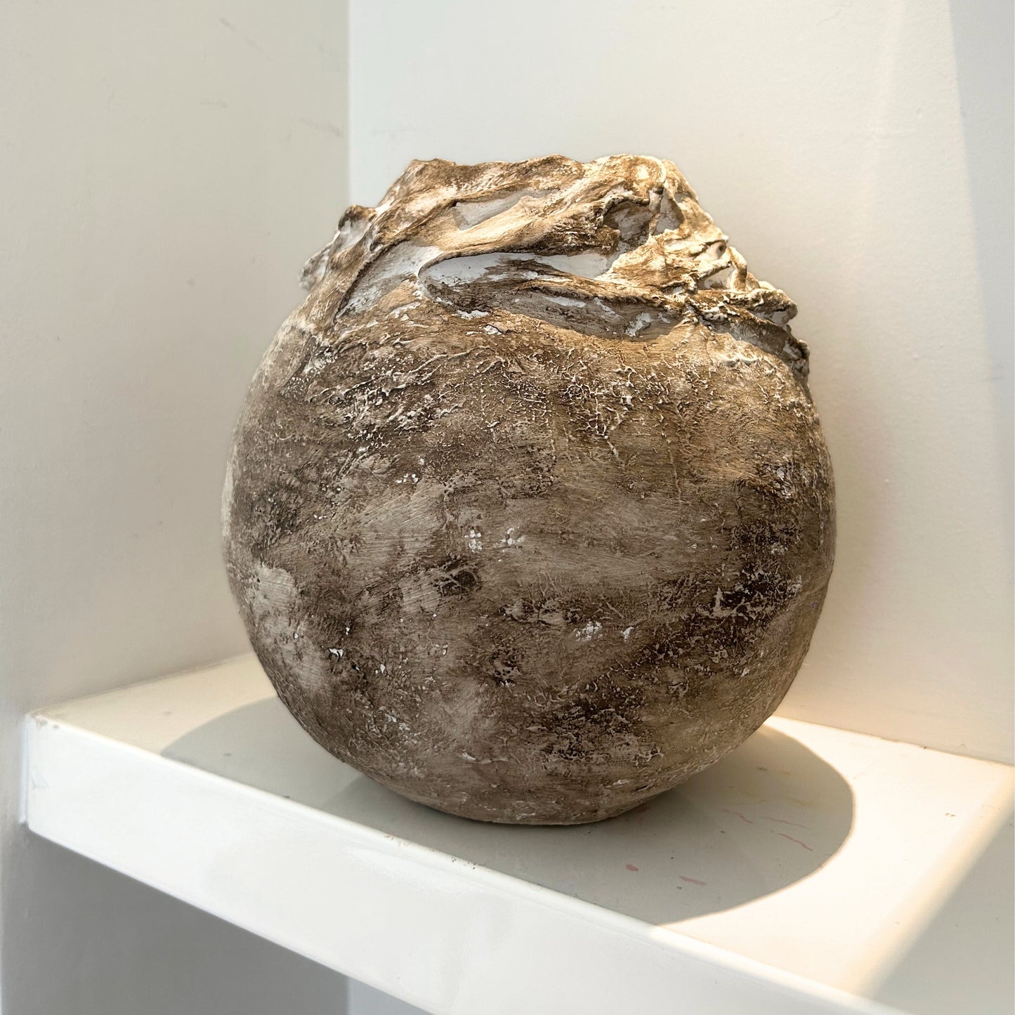 Artistic plaster vase with layered top detail in neutral earthy tones.