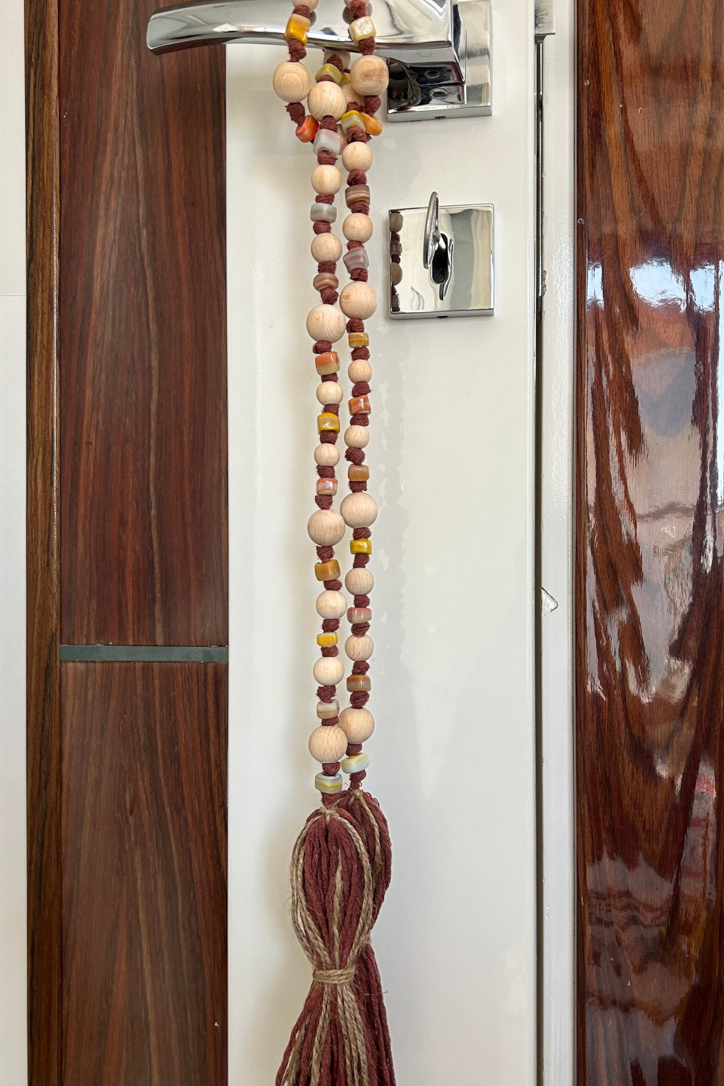 Full view of long beaded curtain tieback with jute tassels in natural decor setting