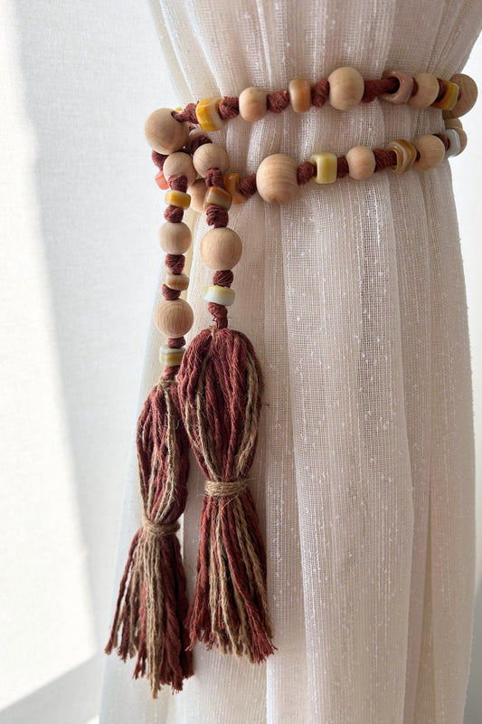 Macrame jute tieback with wooden and glass beads, styled on white curtain