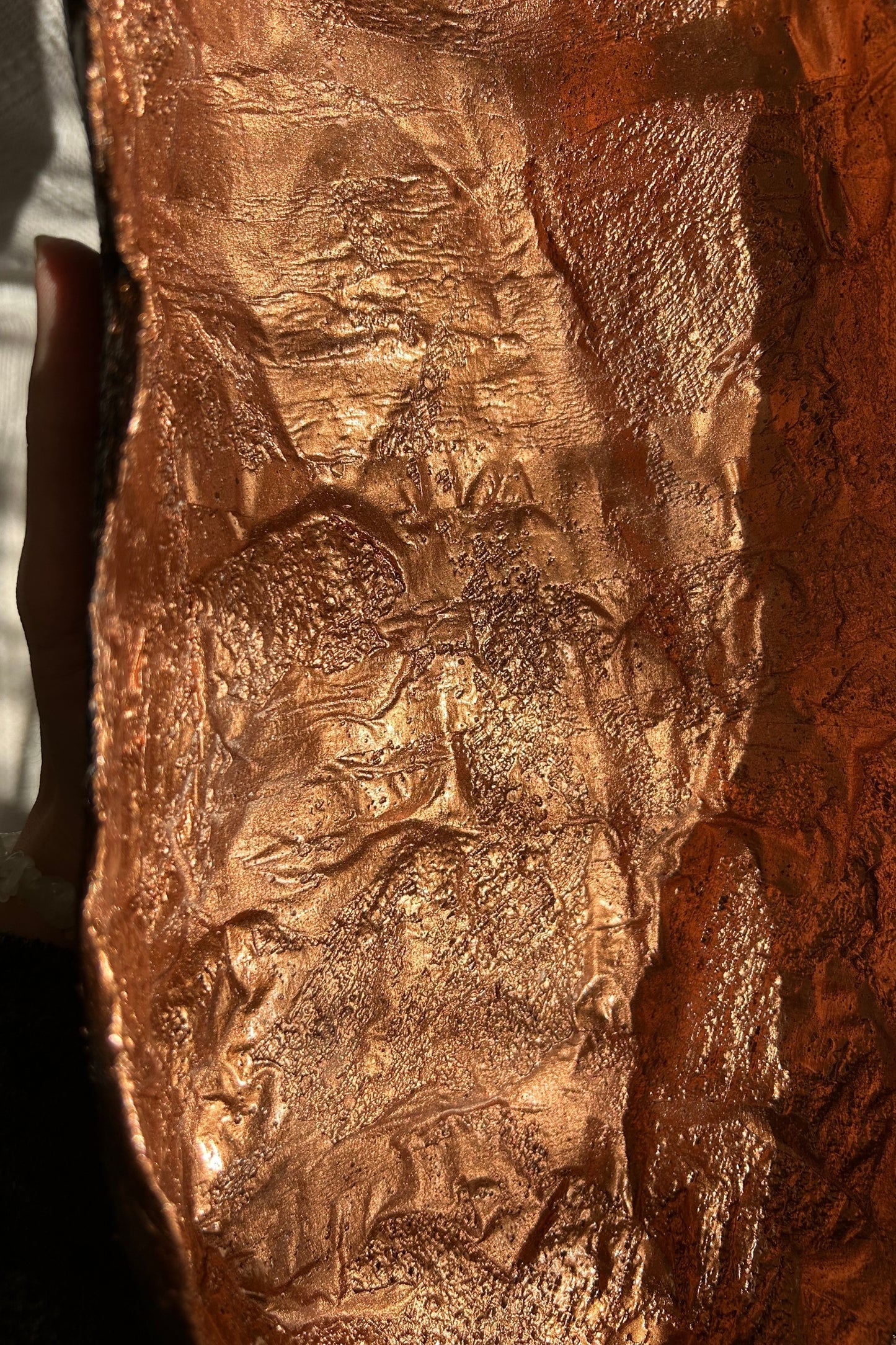 Close-up macro detail of the bowl’s textured copper surface under warm light.