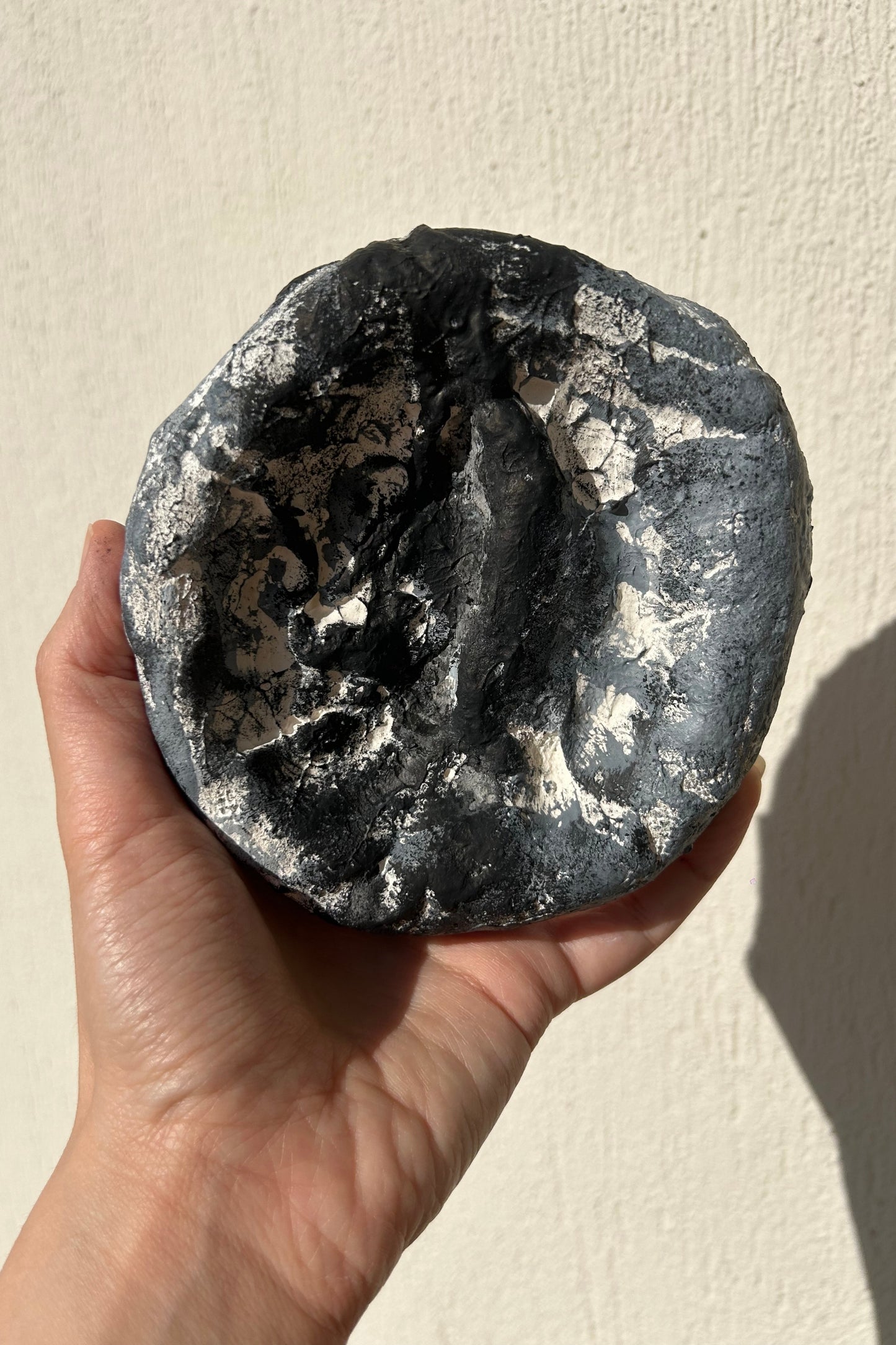 Medium-size handcrafted plaster wall art in textured dark grey tone