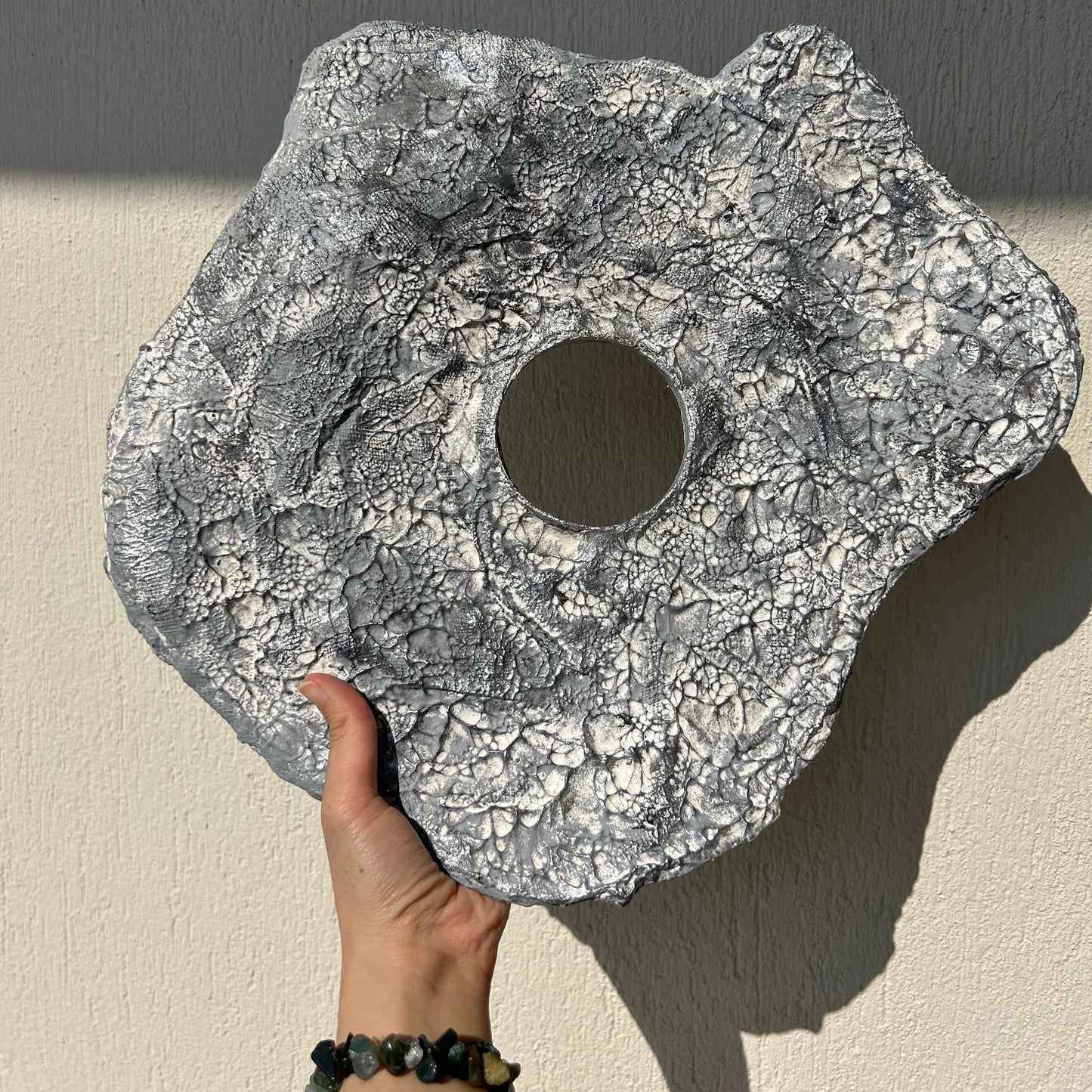 Back side of round silver wall sculpture showing ready-to-hang hook placement