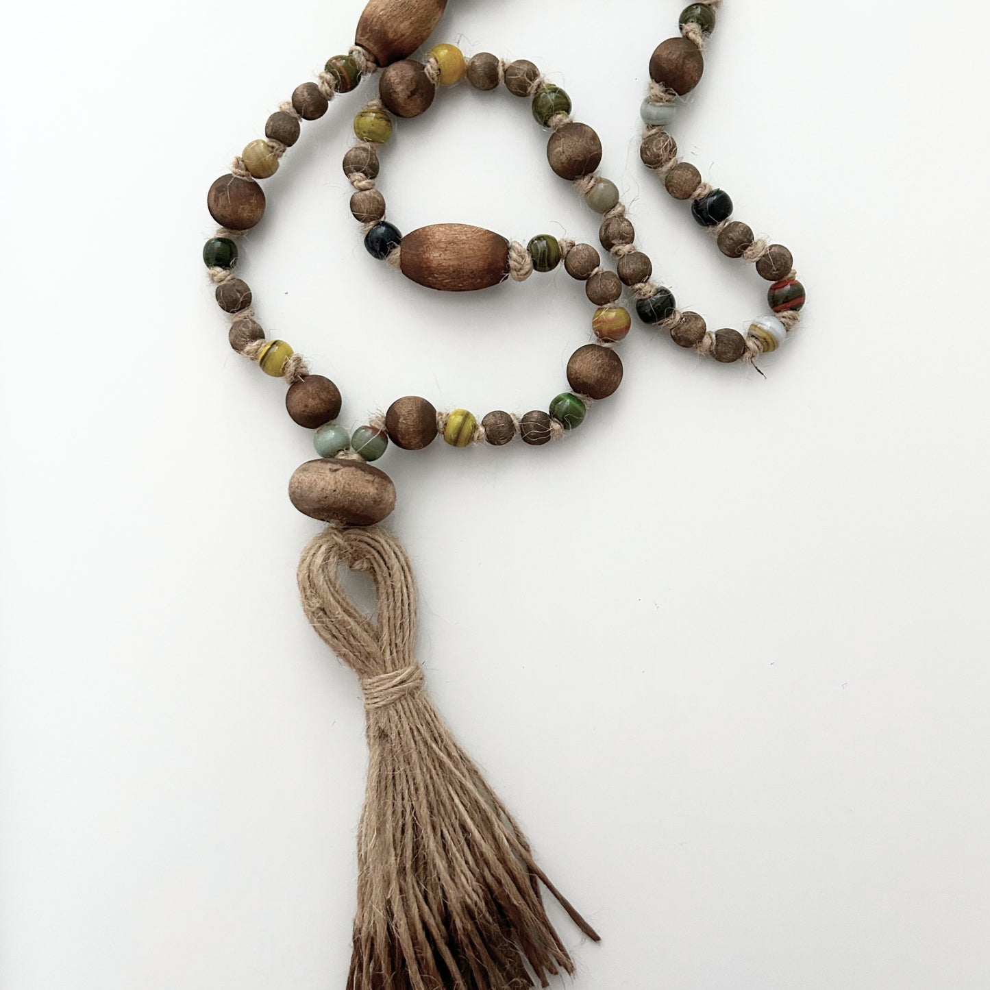 Flatlay view of glass and wooden bead garland with jute tassel