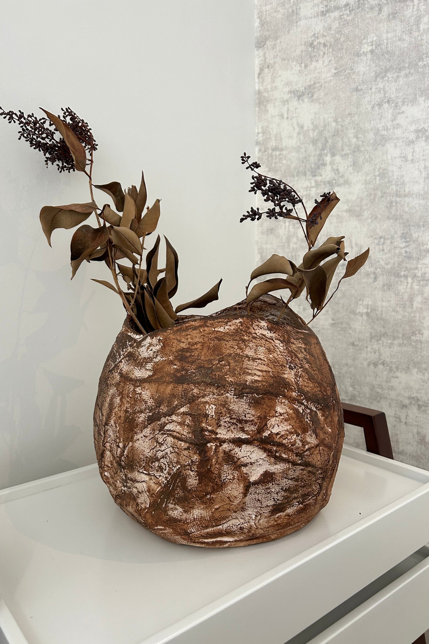Display view of a wabi sabi inspired vase with antique texture and asymmetrical form.