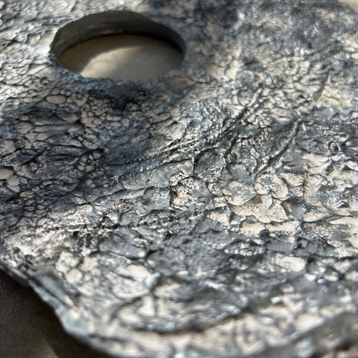 Extreme close-up of handmade coral-like plaster texture with silver shimmer