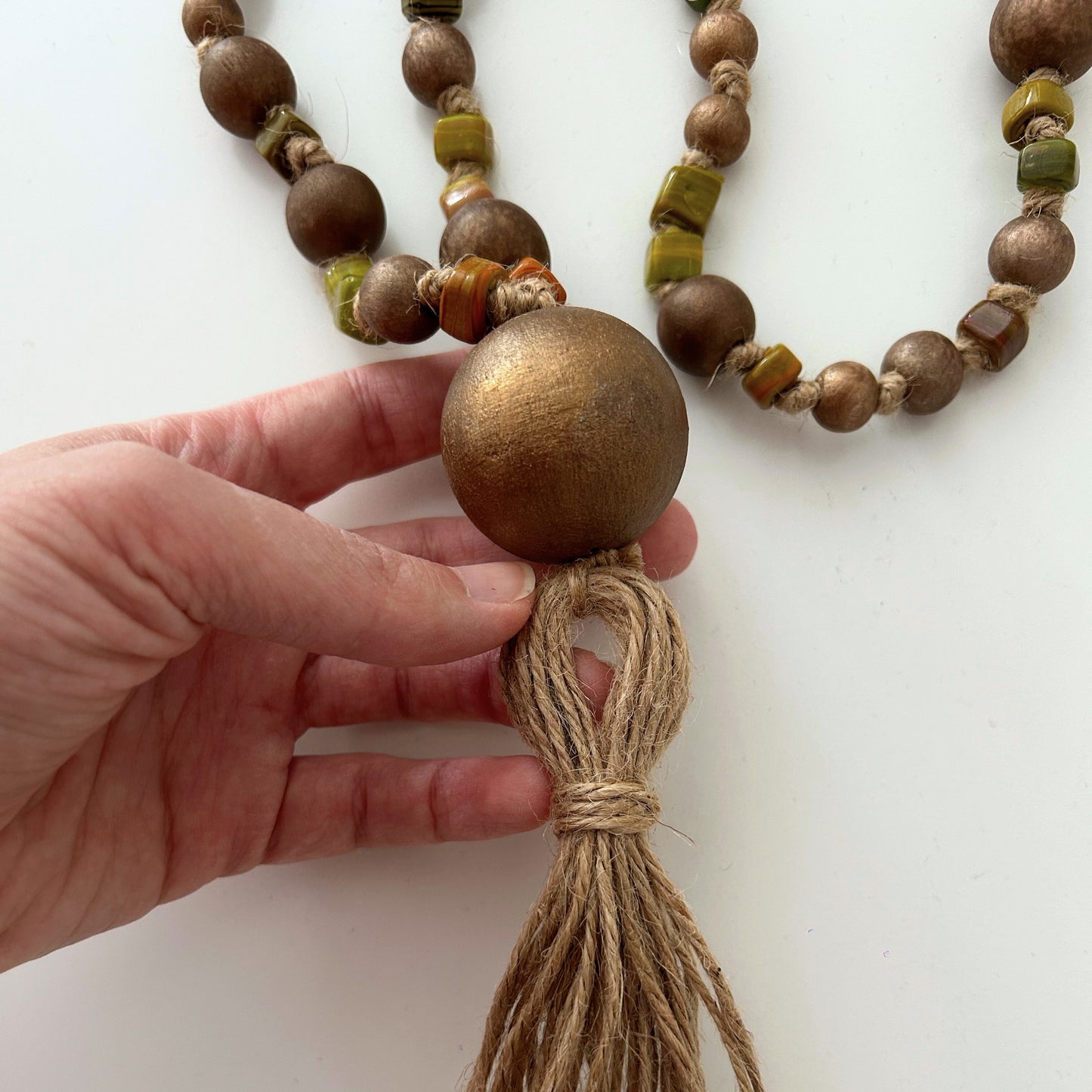 Detailed view of natural jute tassel and large center bead on the garland.