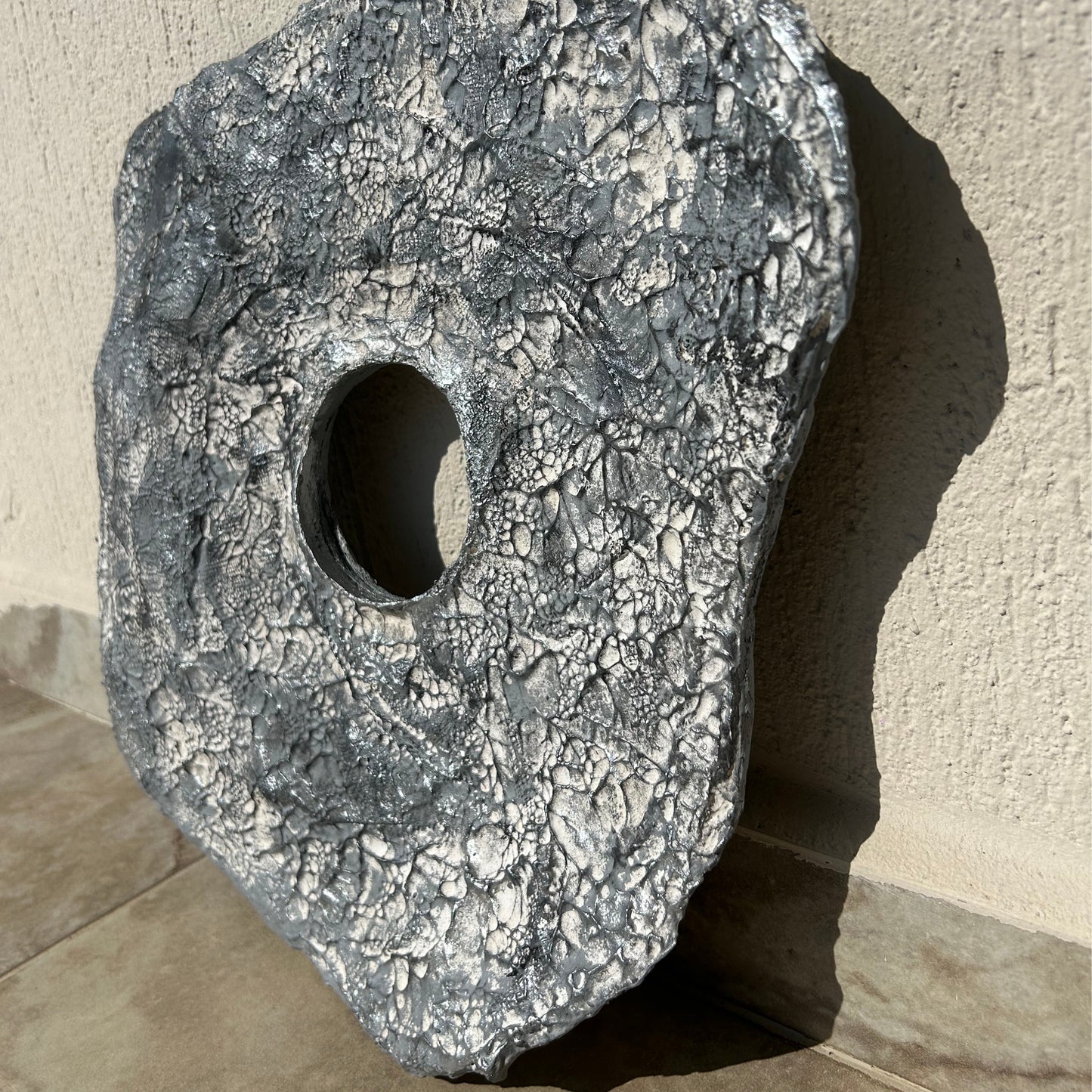 Organic shaped plaster wall art held in hand to show dimension and asymmetry