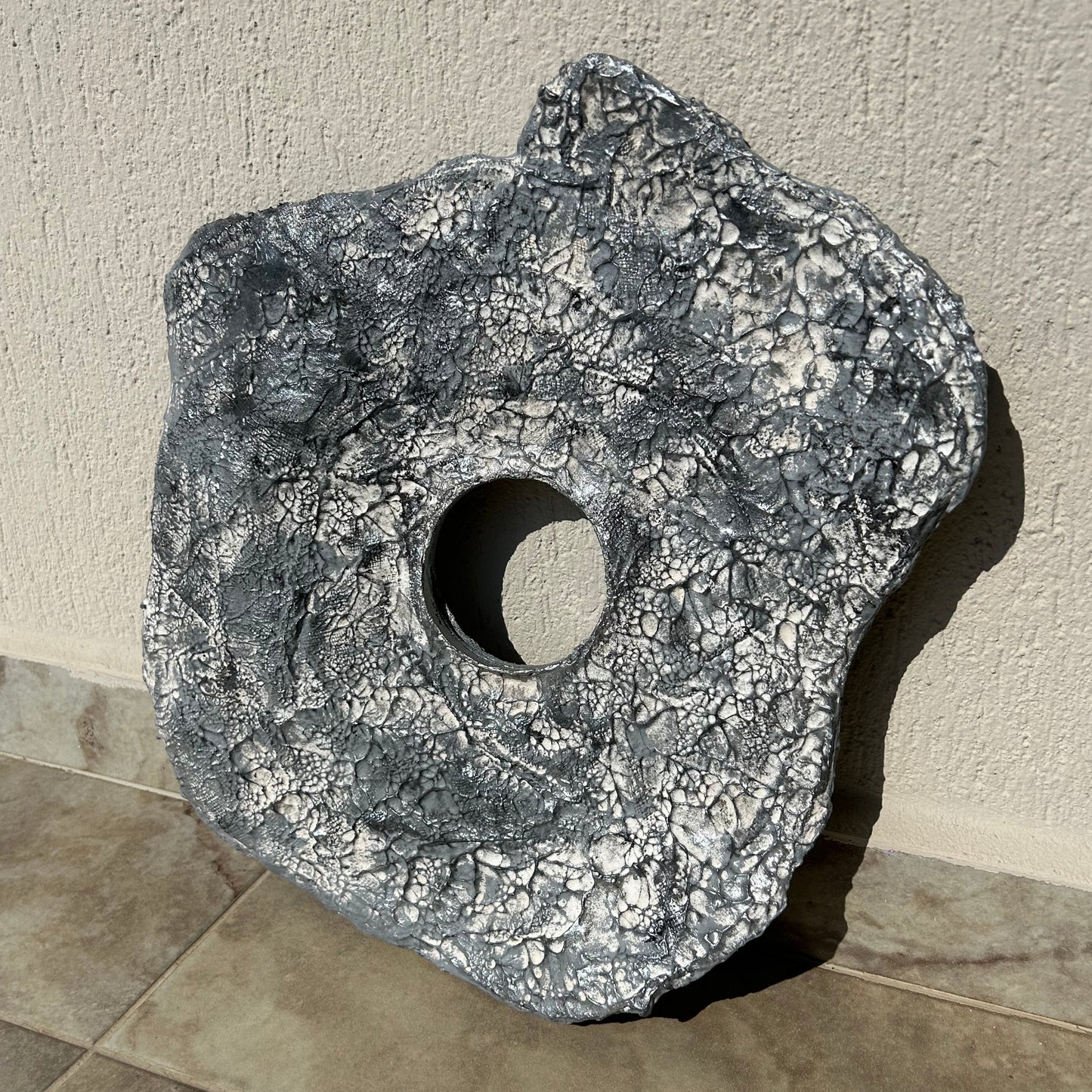 Close-up front view of handmade wabi sabi wall sculpture with soft silver tones