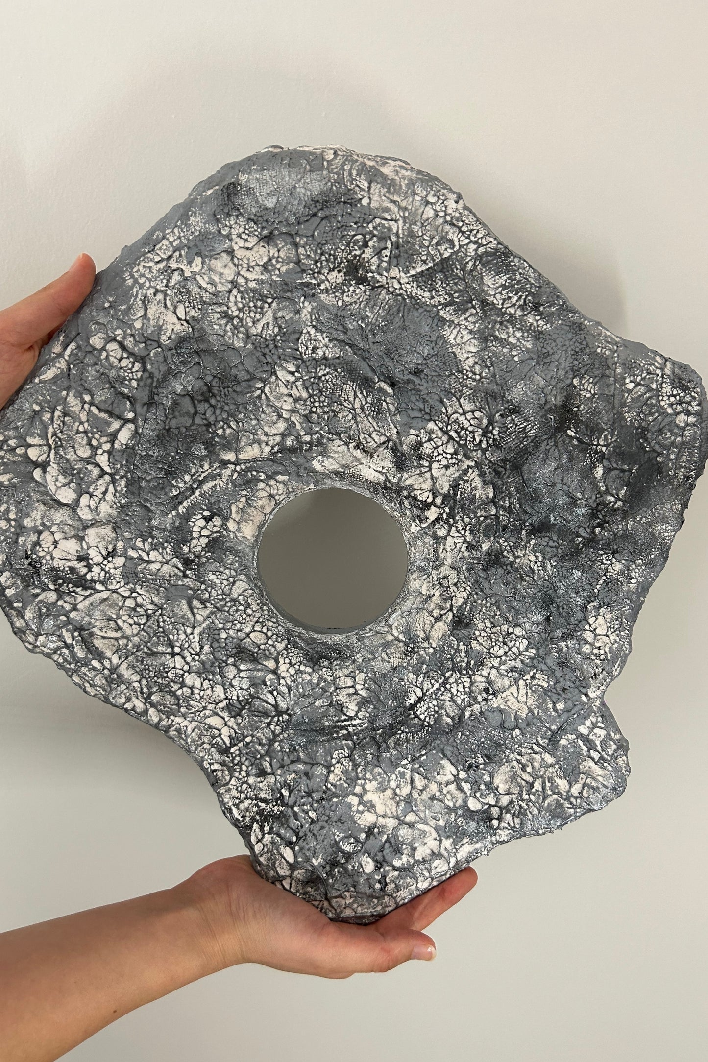 Scale view of the lightweight silver wall sculpture held with one hand