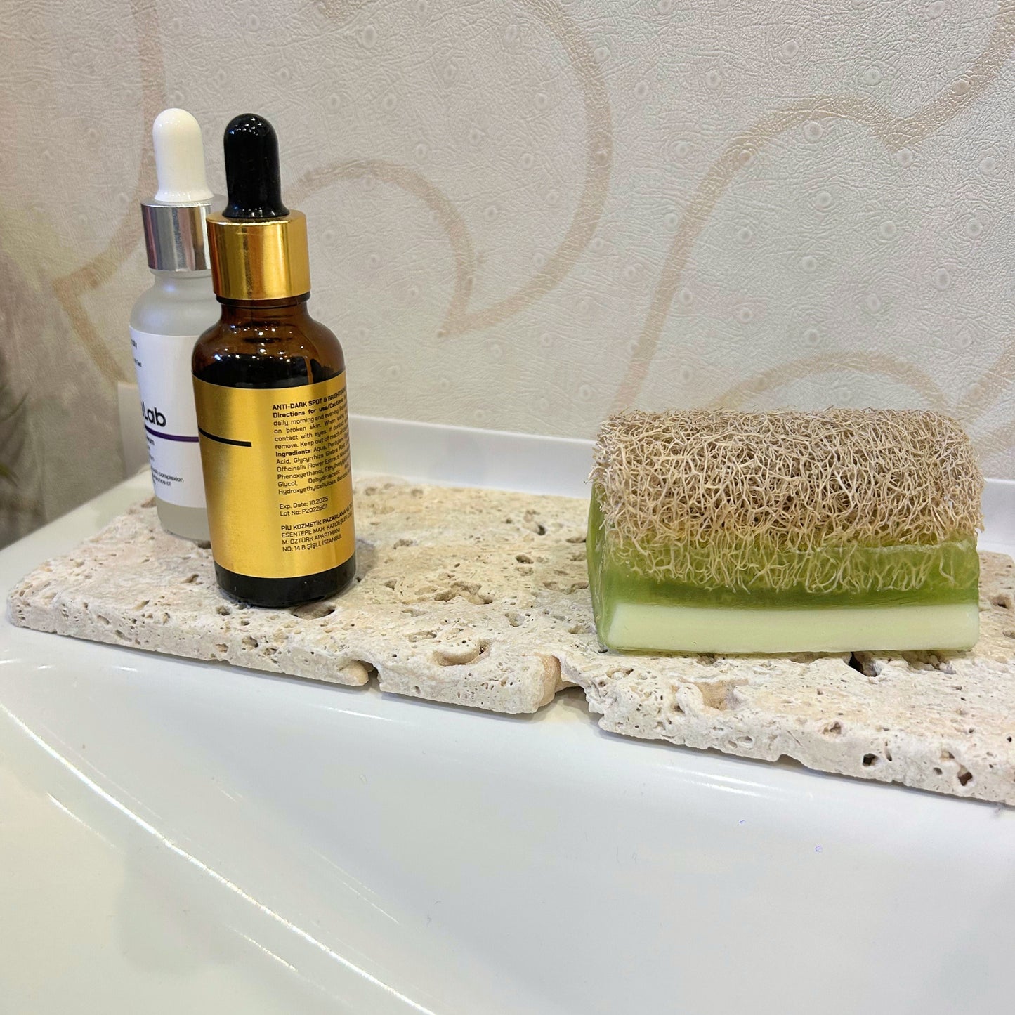 Travertine block styled with essential oil and sponge in a clean bathroom setting