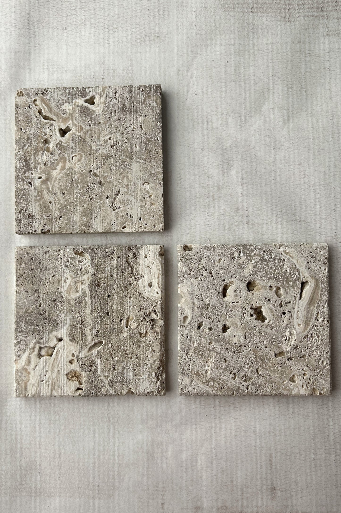 Set of three square travertine display blocks showing porous surface